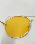 A close-up image of the Casino sunglasses by For Art's Sake® showcases modern eyewear with yellow-tinted lenses and a sleek, stainless steel frame featuring a geometric design. The background is a plain, white surface.