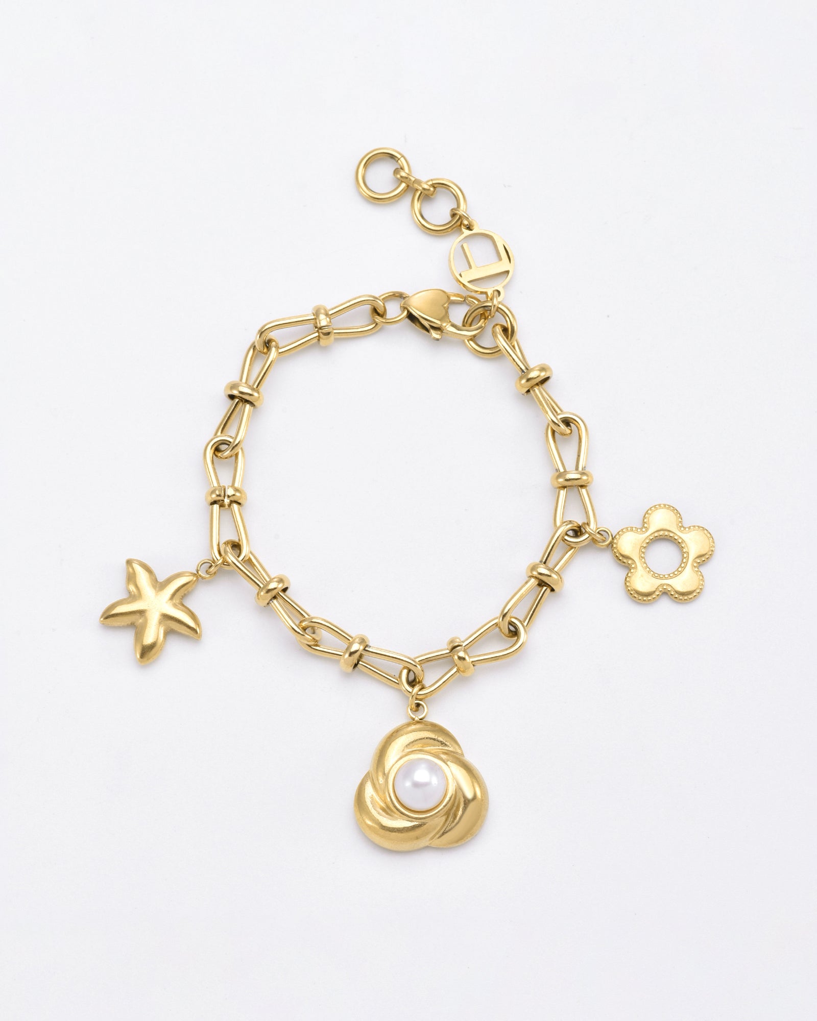 The Daisy Bracelet by For Art's Sake® is a 24-karat gold-plated piece featuring three unique charms: a starfish, a flower, and a rose with a pearl center. The chain is composed of oval links and includes an adjustable clasp with a small round loop for secure fastening. It is elegantly displayed on a plain white background.