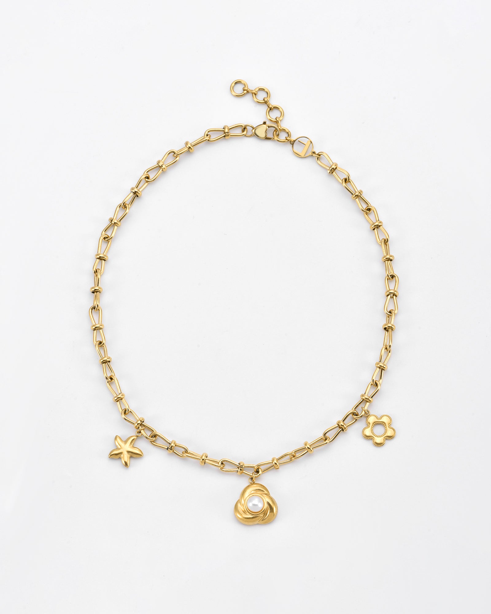 The For Art&#39;s Sake® Daisy Necklace Gold is a 24-karat gold plated chain necklace with a starfish charm, a central charm featuring a freshwater pearl encased in a gold setting, and a daisy flower charm. The necklace has an adjustable clasp closure.