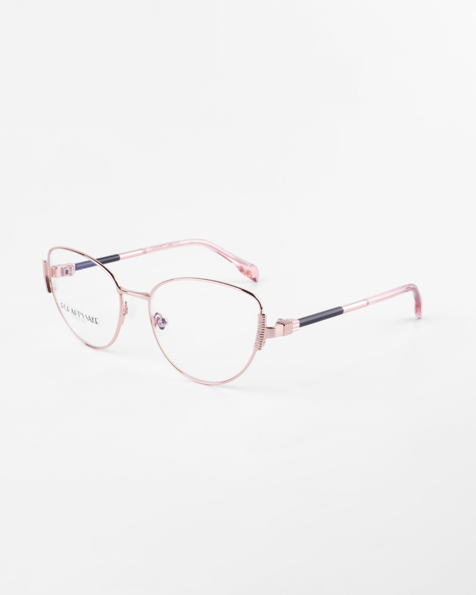 A pair of For Art&#39;s Sake® Dante eyeglasses with thin, rose gold metallic frames and clear prescription lenses. The temple arms are rose gold with black accents near the hinges, and the transparent nose pads include a blue light filter. The eyeglasses are set against a plain white background.