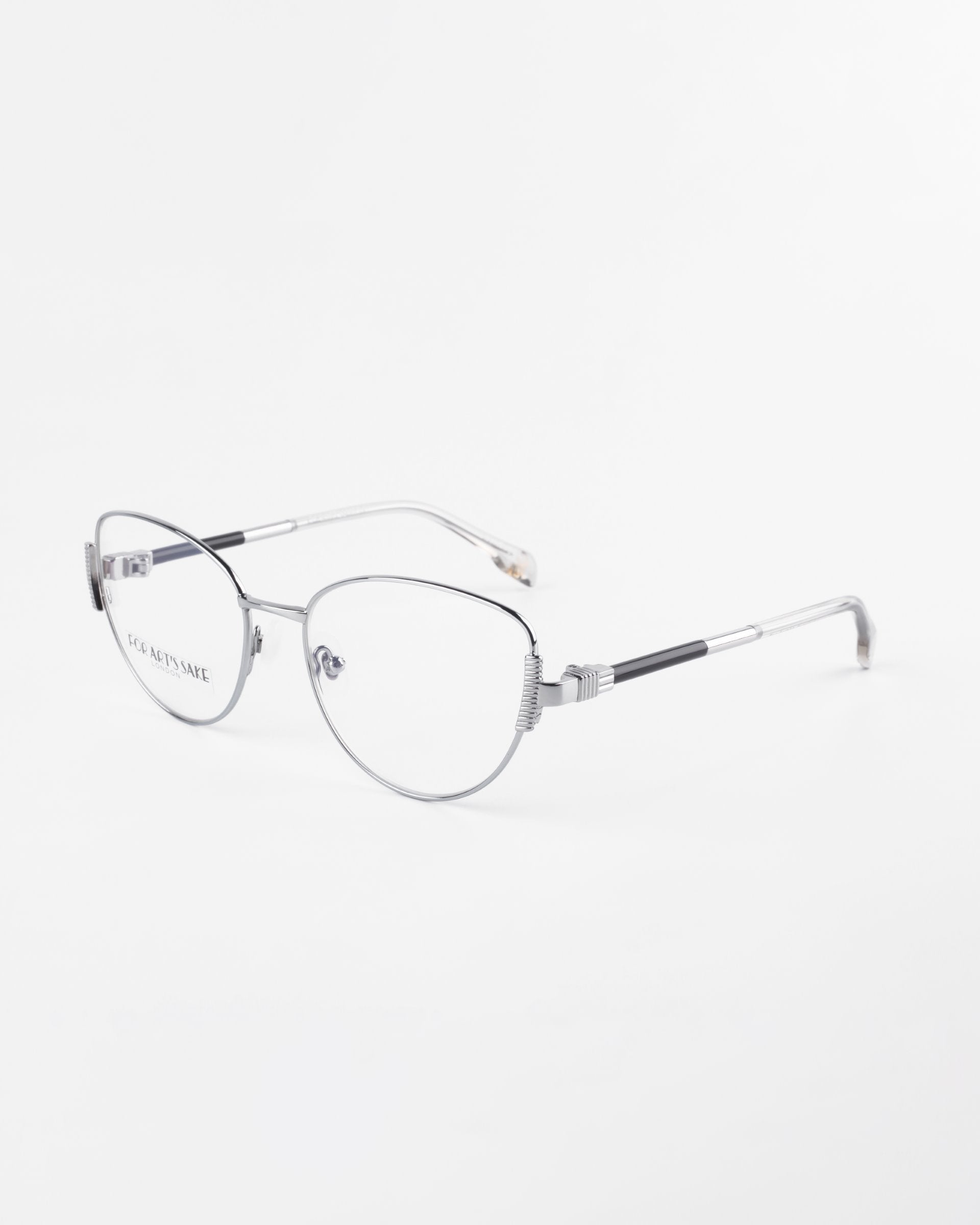 Image of a pair of For Art&#39;s Sake® Dante eyeglasses with thin, silver metal frames. The temples feature a subtle black accent near the hinges. The clear prescription lenses have a modern and minimalist style. These glasses also include jade stone nose pads for added comfort. The background is plain white.