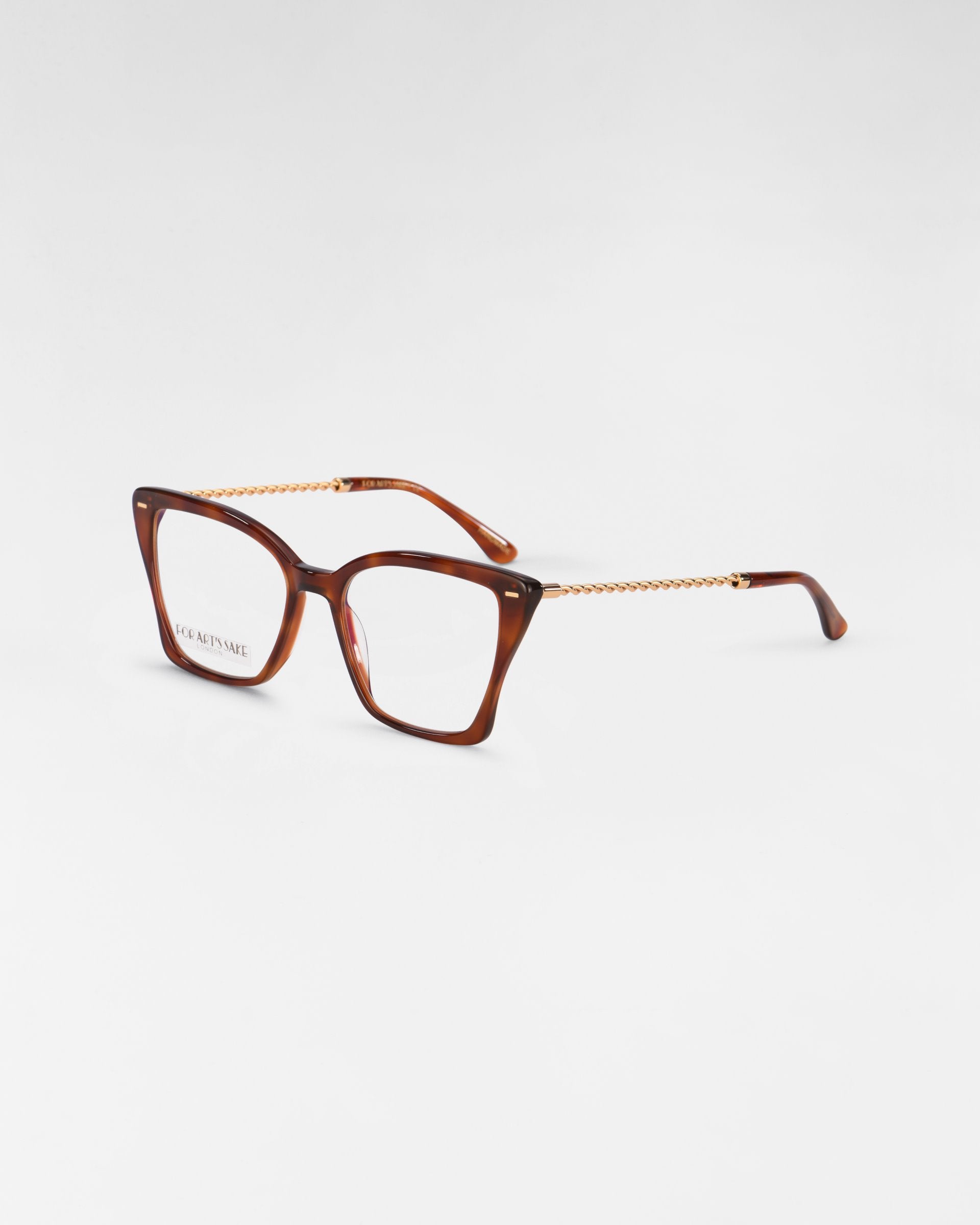 A pair of For Art&#39;s Sake® Dion eyeglasses with thick, tortoiseshell frames and gold chain arms is displayed on a plain white background. The design is stylish and modern, combining bold square lenses with UV protection and elegant, twisted gold temples.