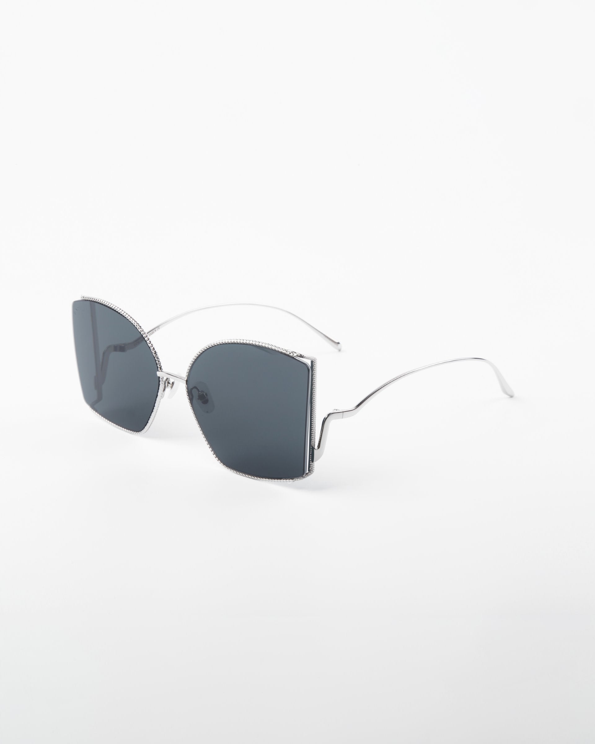 A pair of stylish, oversized, square-shaped Dixie sunglasses with dark lenses and thin, handmade gold-plated frames. The glasses, from the brand For Art&#39;s Sake®, feature a minimalist and sleek design with UV protection, laid on a plain white background.