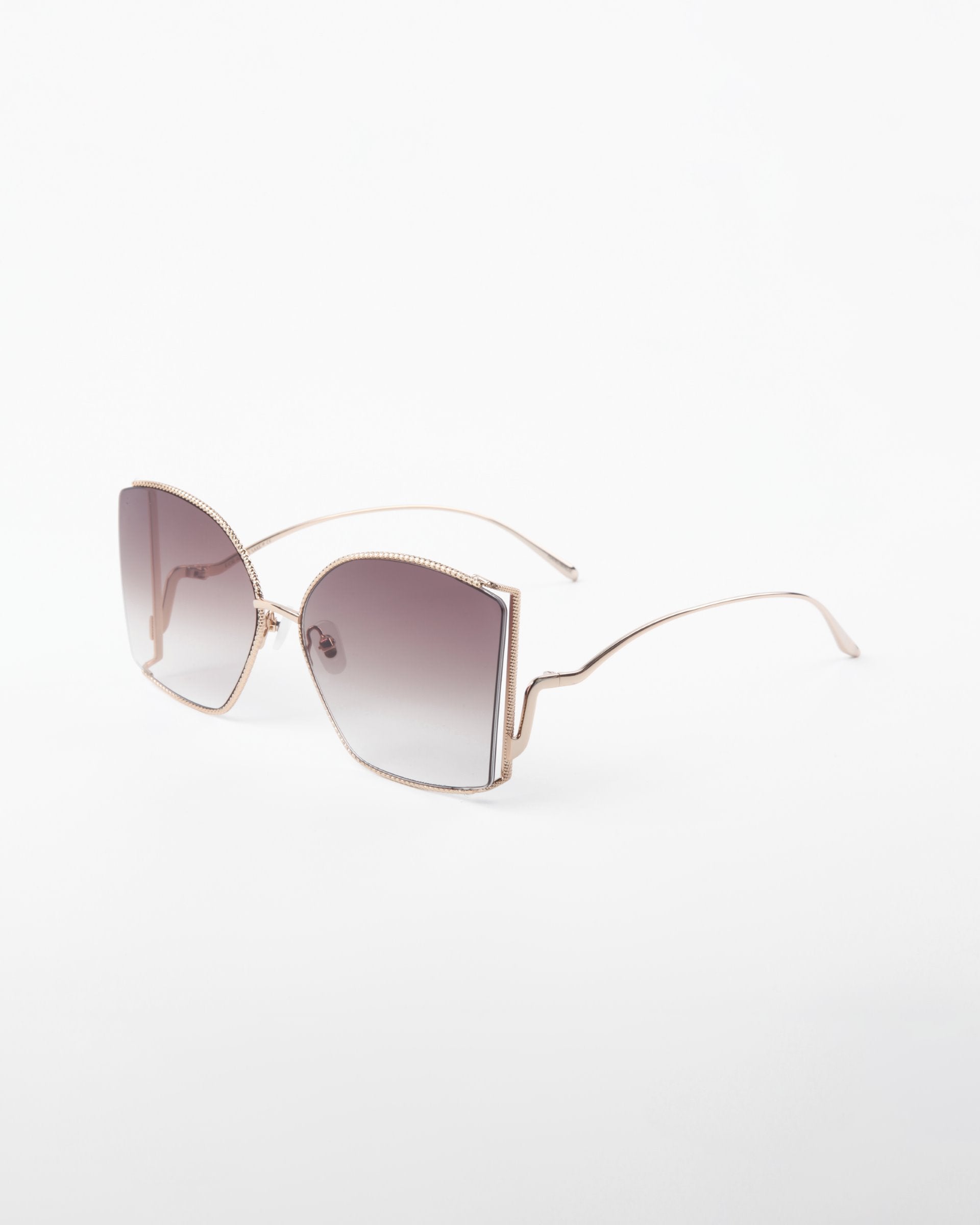 A pair of stylish, oversized For Art&#39;s Sake® Dixie sunglasses featuring UV protection and a thin, handmade gold-plated frame. The shatter-resistant nylon lenses boast a gradient fade from a darker tint at the top to a lighter tint at the bottom, with an elegant curve at the nose bridge and curved temple tips.