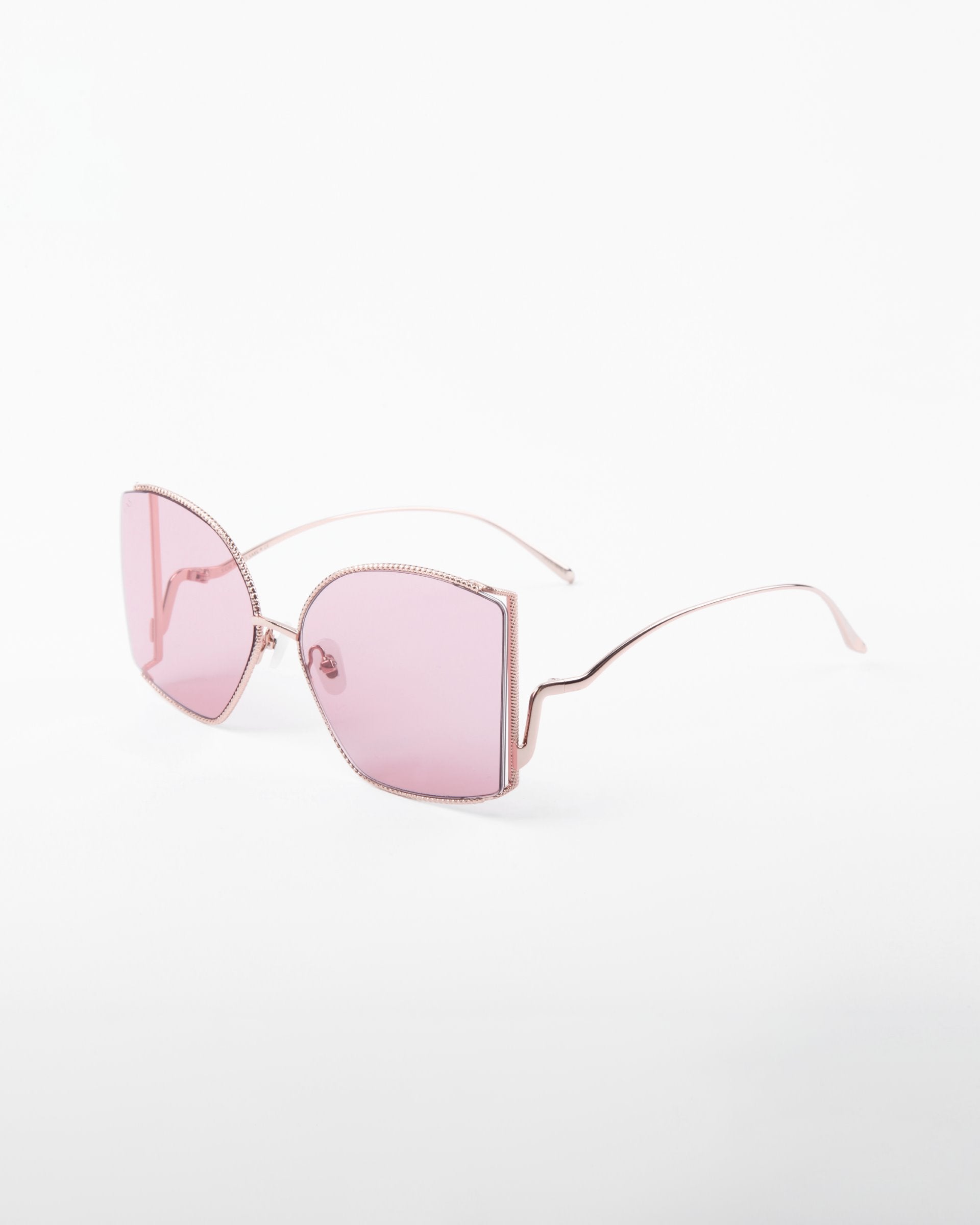 Sleek pair of Dixie sunglasses by For Art&#39;s Sake® with oversized square frames and light pink, shatter-resistant nylon lenses. The thin temples and rims feature delicate, handmade gold-plated frames. Offering UV protection, these sunglasses are set against a plain white background.