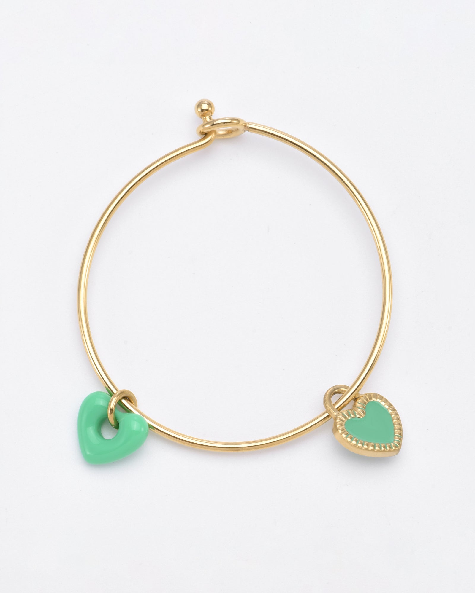 A minimalistic, delicate Double Heart Bracelet Gold featuring two heart-shaped charms by For Art's Sake®. One charm is a smooth, solid green heart, while the other is a decorated gold heart with a green center. The 24k gold plating adds an extra touch of elegance. The bracelet is set against a plain white background.