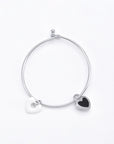 Simple silver bracelet with two heart-shaped charms: one white and one black with a silver outline. This elegant Double Heart Bracelet Silver by For Art's Sake® features a small clasp and is displayed against a white background.