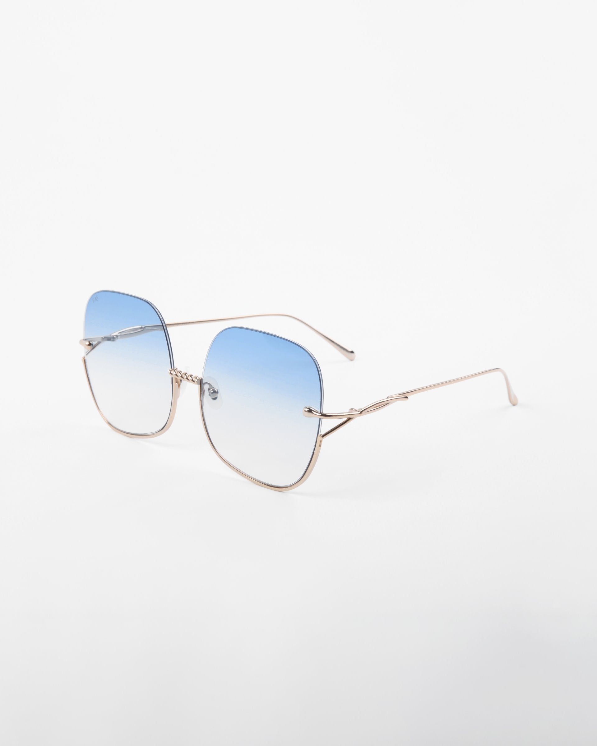 A pair of Duchess sunglasses by For Art&#39;s Sake® with blue gradient, shatter-resistant lenses and thin, handmade gold-plated frames. These stylish sunglasses offer UVA &amp; UVB protection and are placed on a plain white background.
