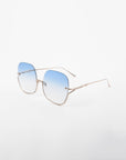 A pair of Duchess sunglasses by For Art's Sake® with blue gradient, shatter-resistant lenses and thin, handmade gold-plated frames. These stylish sunglasses offer UVA & UVB protection and are placed on a plain white background.