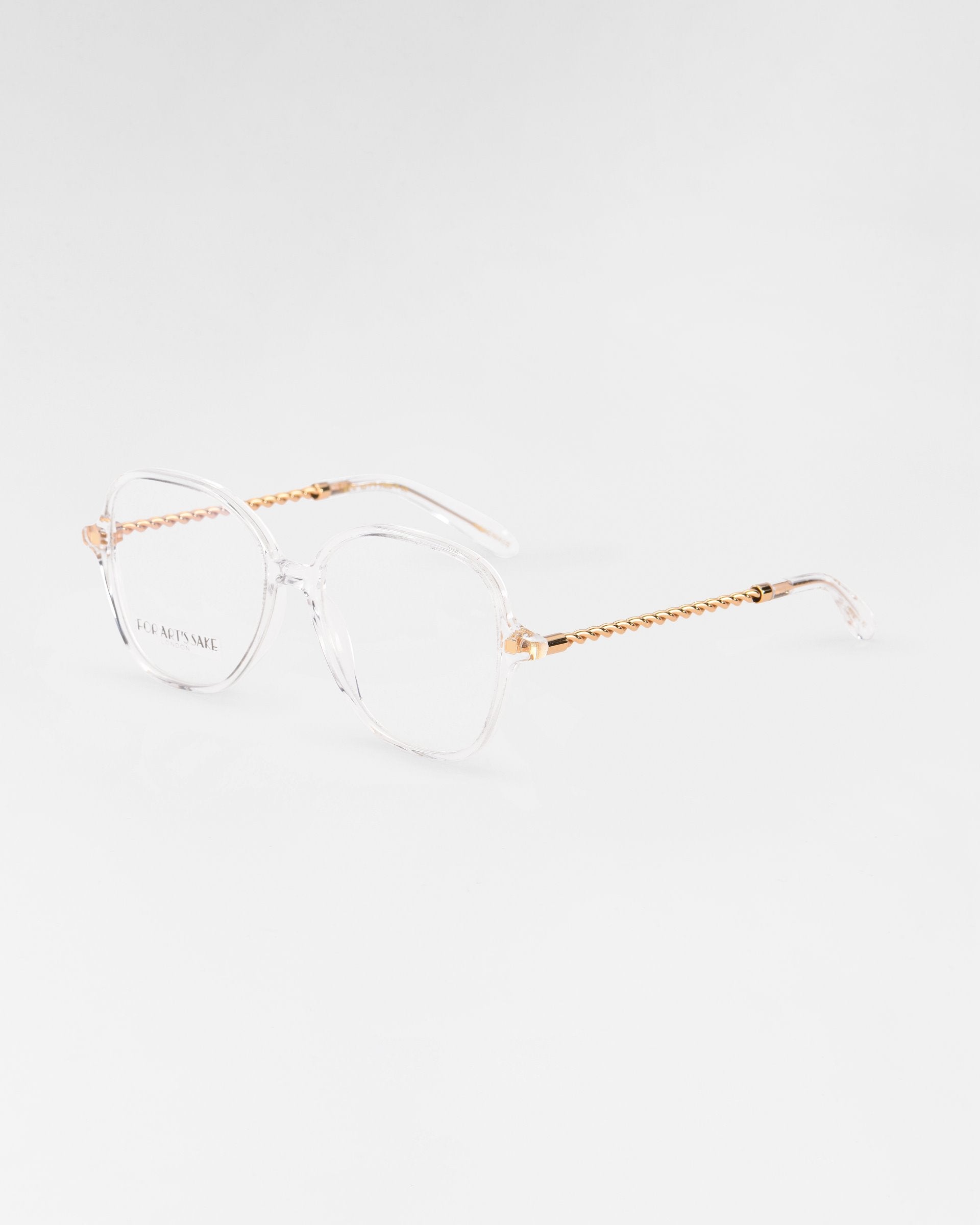 A pair of transparent Dumpling eyeglasses with hexagonal frames and golden, beaded temples by For Art&#39;s Sake®. The lenses are large and slightly oversized, offering a modern and stylish look with the added benefit of a blue light filter. The background is plain white, highlighting the glasses&#39; design details.