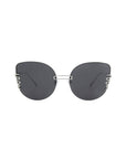 A pair of stylish, oversized cat-eye sunglasses with dark lenses and a unique frame design. The frames feature a silver metal bridge and decorative silver elements on the outer edges of the lenses, adding a touch of elegance to the overall minimalist look. Plus, they offer 100% UV protection. These are the Girlboss by For Art's Sake®.