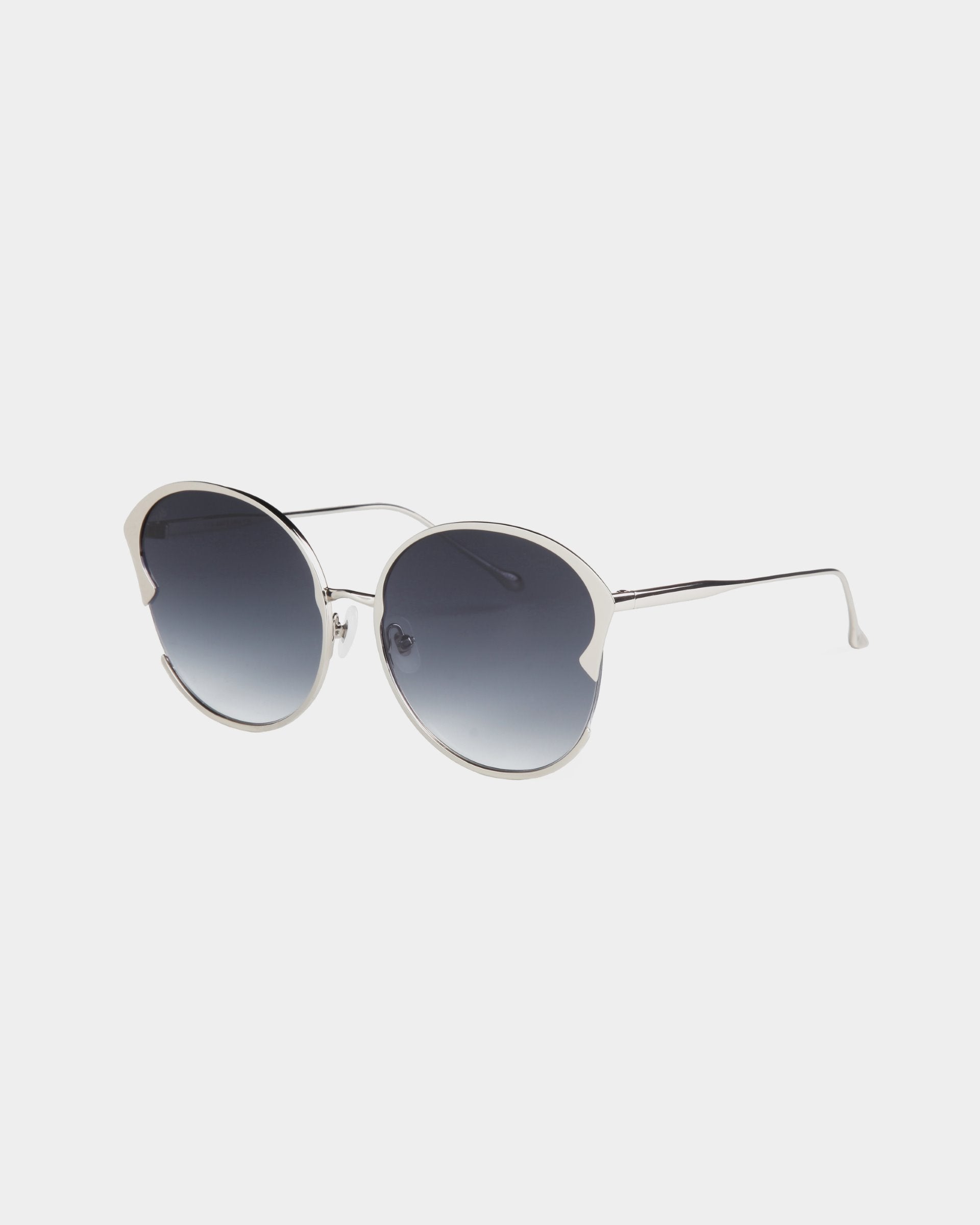 A pair of stylish round Alectrona sunglasses by For Art&#39;s Sake® with silver frames and dark gradient, shatter-resistant lenses. The temples are thin and metallic with a slight curve at the ends. The design includes adjustable jade nose pads and a unique cut-out detail at the top corners of the lenses.