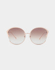 The Alectrona sunglasses by For Art's Sake® feature stylish round nylon lenses with a soft gradient tint transitioning from dark to light. The sleek frame is a sophisticated light pinkish gold, accentuated by a subtle cat-eye shape at the corners. These UVA & UVB-protected glasses come with a faux leather case and have thin arms extending back towards the earpieces.