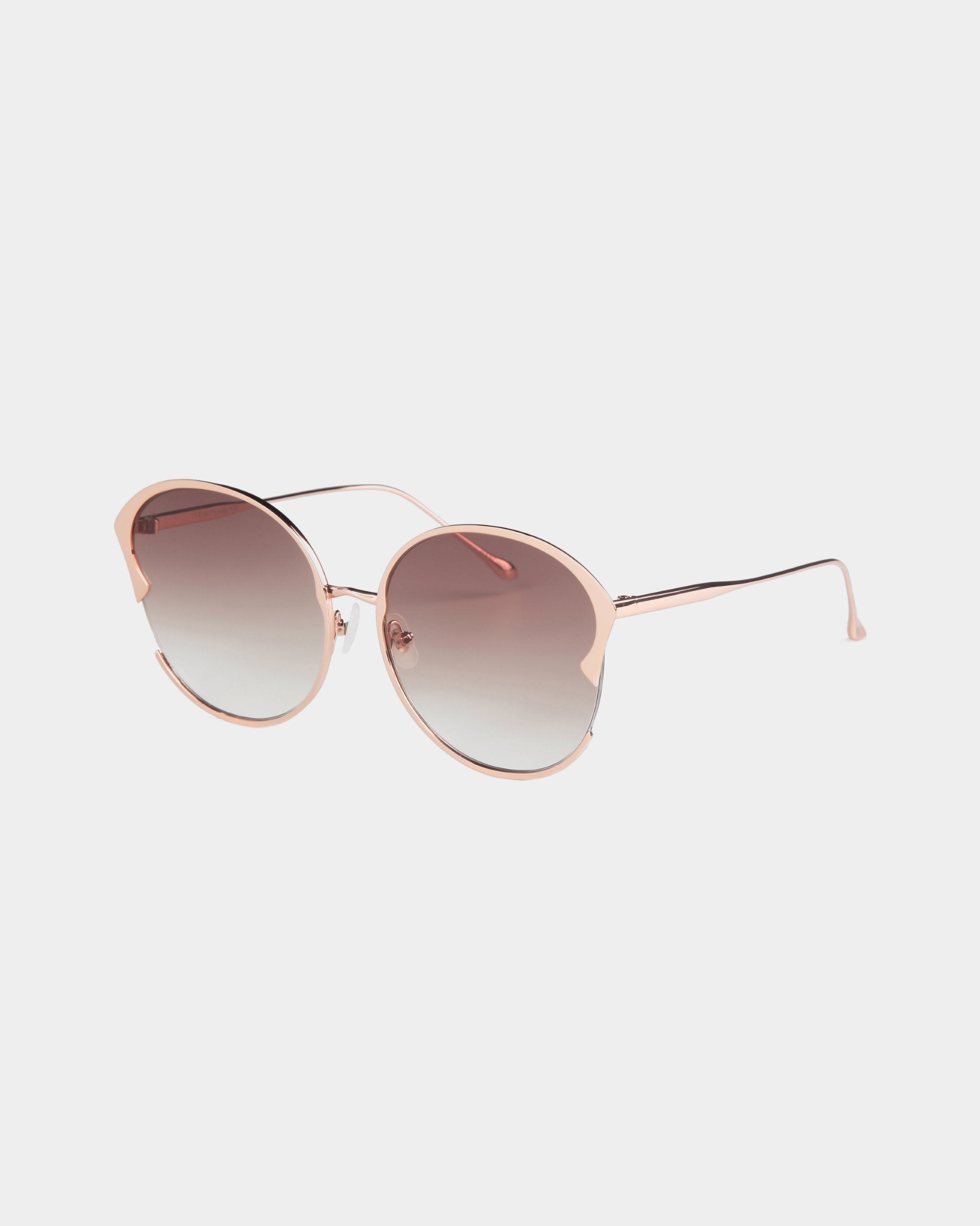 A pair of stylish **For Art&#39;s Sake® Alectrona** sunglasses with an 18-karat gold-plated light pink metallic frame and gradient, shatter-resistant lenses. The lenses are darker at the top and gradually lighten towards the bottom. The design is modern with a slight cat-eye shape, thin curved temples, and adjustable jade nose pads.
