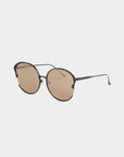 The Alectrona by For Art's Sake® features stylish round sunglasses with thin black frames and light brown, UV-protected nylon lenses. These sunglasses have a minimalist design equipped with slightly curved arms and nose pads for added comfort. They come in a sleek faux leather case and are presented against a white background.