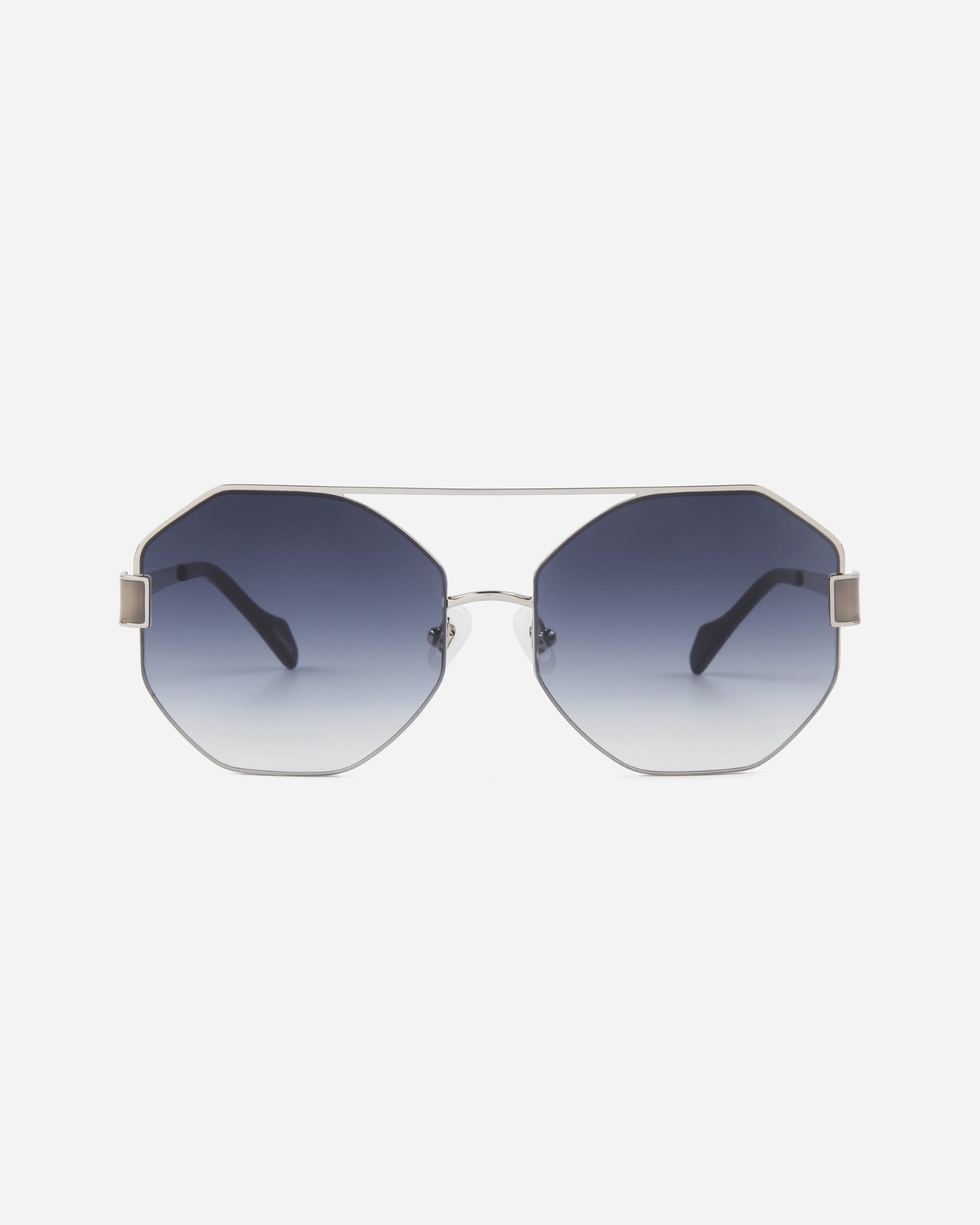 A pair of stylish Mania sunglasses by For Art&#39;s Sake® featuring octagonal, nylon lenses with a gradient tint from dark blue at the top to light at the bottom. The stainless steel frames are thin and metallic, with black temple arms and adjustable nose pads for comfort. The background is plain white.
