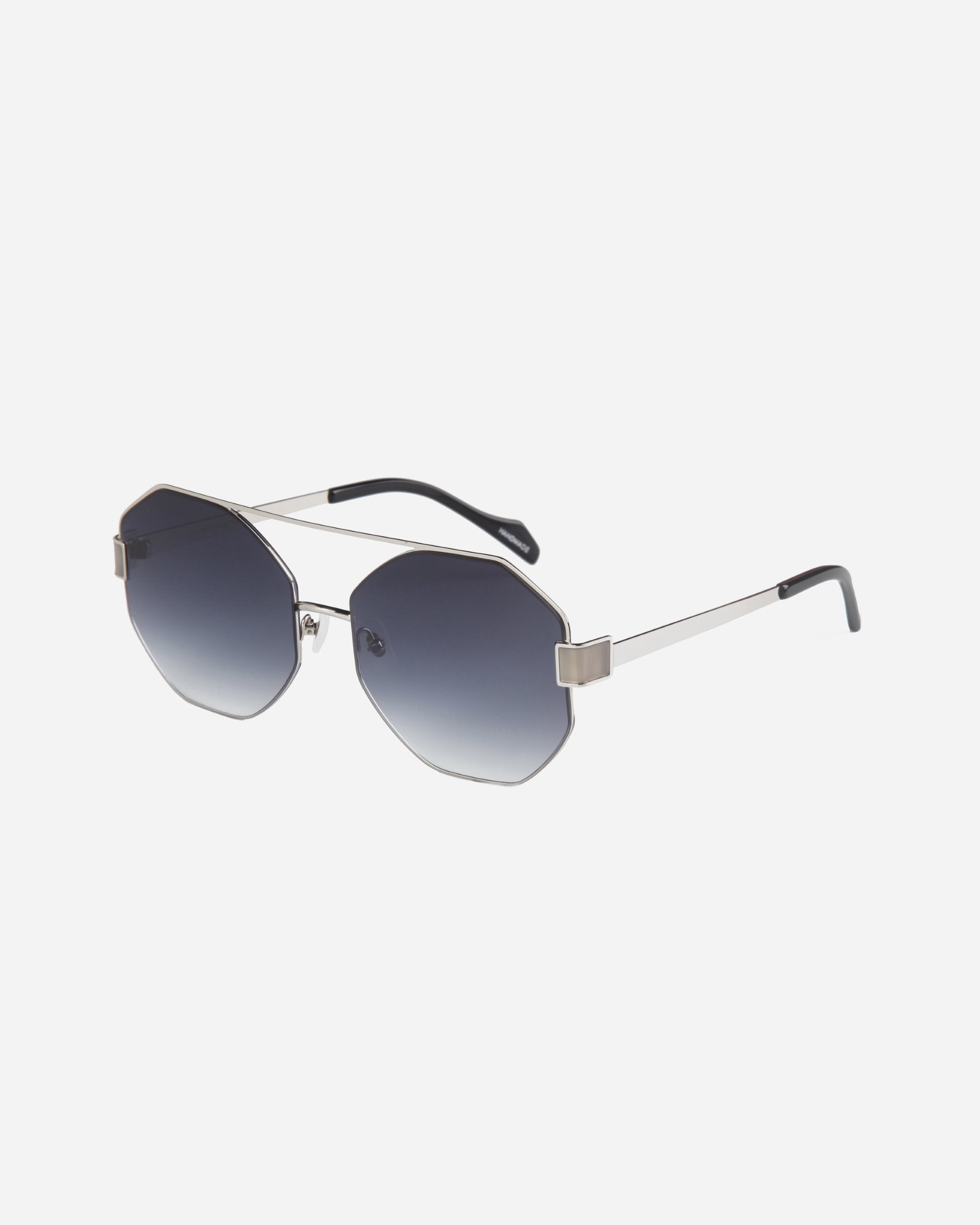 A pair of stylish For Art&#39;s Sake® Mania sunglasses with octagonal nylon lenses featuring a gradient tint from dark at the top to lighter at the bottom. The stainless steel frame boasts a sleek, minimalist design, and the temples are thin with black tips. Adjustable nosepads ensure a comfortable fit for all-day wear.