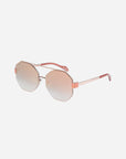 A pair of stylish **For Art's Sake® Mania** sunglasses with hexagonal stainless steel frames in rose gold, featuring slightly gradient nylon lenses that transition from pink to a lighter hue. The arms are slender with matching rose gold detailing and pink temple tips, plus adjustable nosepads for added comfort.