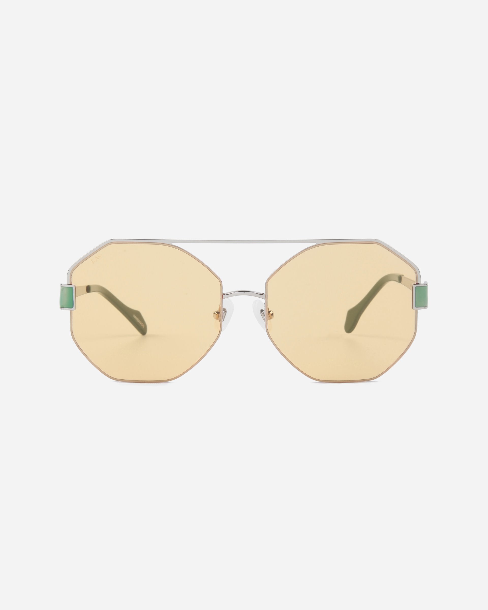 Hexagonal sunglasses with light yellow Nylon lenses and silver stainless steel frames. The Mania by For Art&#39;s Sake® sunglasses feature adjustable nosepads, green temple tips, and a minimalist design, set against a plain white background.