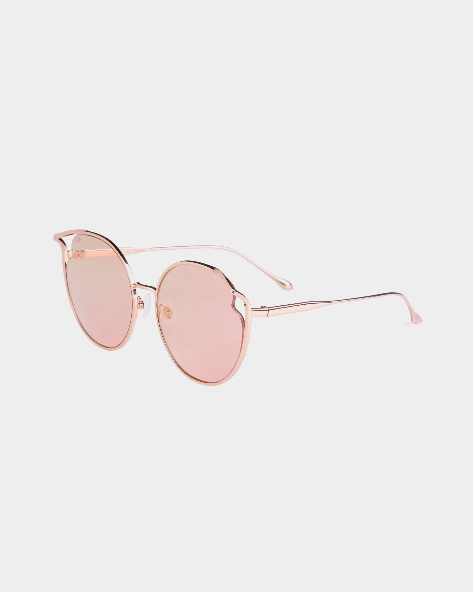 The For Art&#39;s Sake® Cat sunglasses boast round, pink-tinted nylon lenses encased in a thin gold frame. Featuring a delicate bridge and jadestone nosepads for enhanced comfort, the design is complemented by gold arms with curved ends to ensure a secure fit. These stylish glasses are presented against a plain white background.