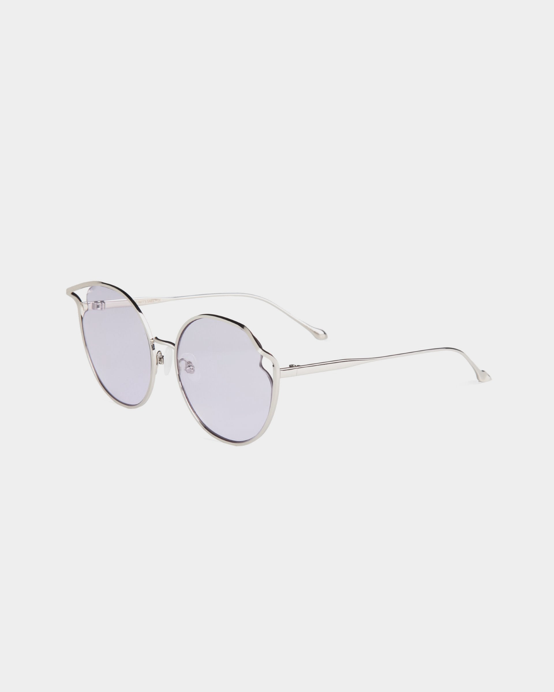 For Art's Sake® presents the Cat, a pair of round, wire-framed sunglasses with thin, silver-toned arms and grey-tinted nylon lenses. Featuring UVA & UVB-protected lenses and a curved bridge, these sunglasses boast a minimalistic design and adjustable nosepads, set against a plain white background.