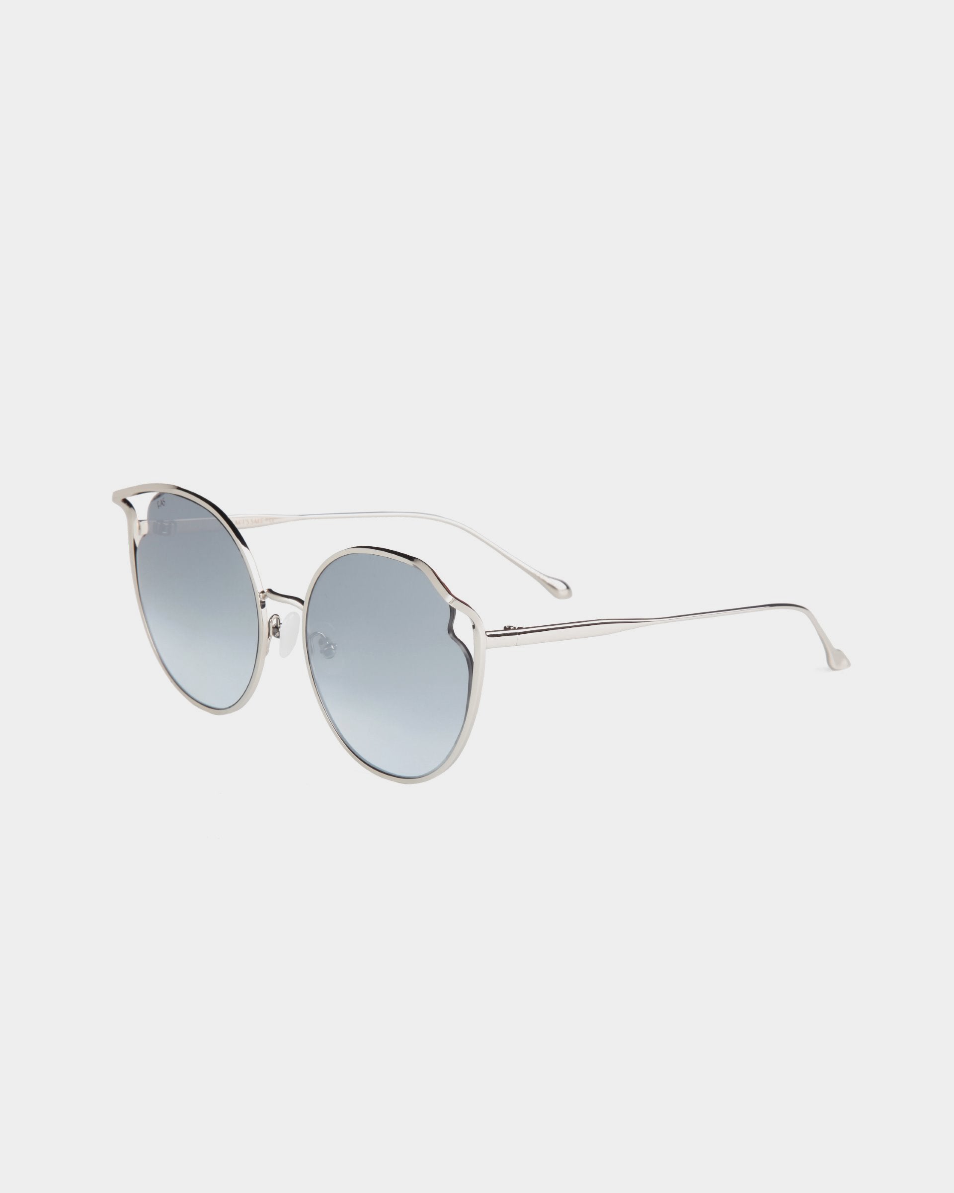 A pair of &quot;Cat&quot; by For Art&#39;s Sake® silver round sunglasses with gradient blue, UVA &amp; UVB-protected nylon lenses. The metal frames are sleek and minimalist, featuring a thin bridge, jadestone nose pads, and arms. The sunglasses are placed on a plain white background.