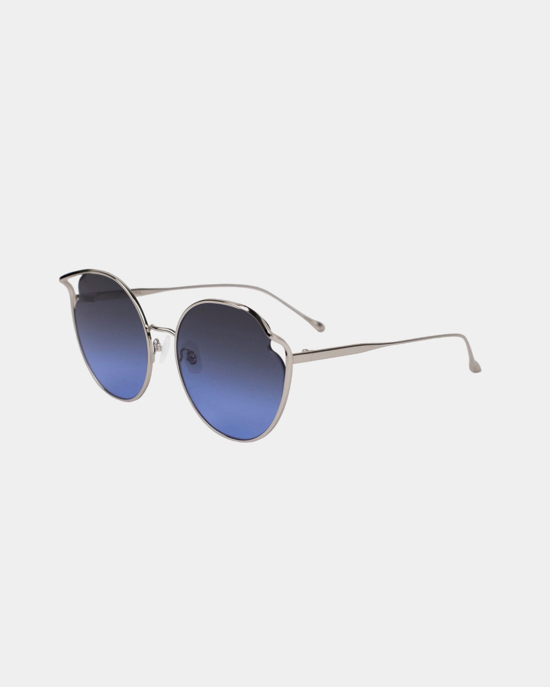 A pair of stylish Cat sunglasses from For Art's Sake® featuring round, dark blue gradient nylon lenses and thin silver metal frames. The temples are sleek, with a slight curve at the ends for a secure fit. With UVA & UVB protection and adjustable nosepads, the design is modern and elegant, suitable for both casual and formal wear.