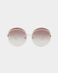 The For Art's Sake® Quartz sunglasses feature thin stainless steel frames and round gradient nylon lenses that transition from dark to light. These stylish glasses include subtle detailing near the temples and a slim gold bridge connecting the lenses. With UVB-protected lenses, they offer both sophistication and protection against the sun, all set against a plain white background.