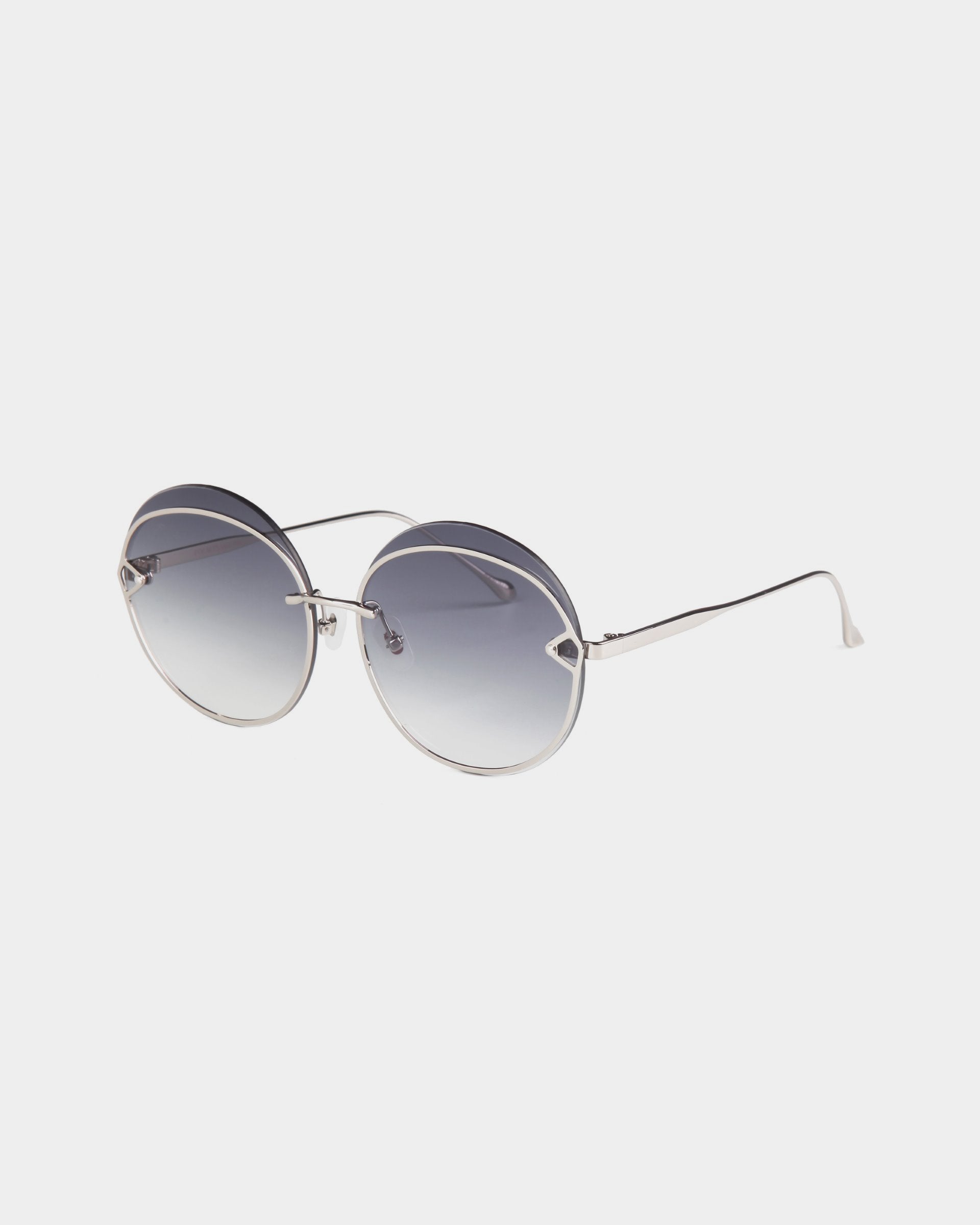 The Quartz sunglasses from For Art's Sake® feature round, gradient blue nylon lenses set in thin, UVB-protected stainless steel frames. The slim silver arms extend from the round lenses with a graceful curve at the ends, all set against a clean, white background.