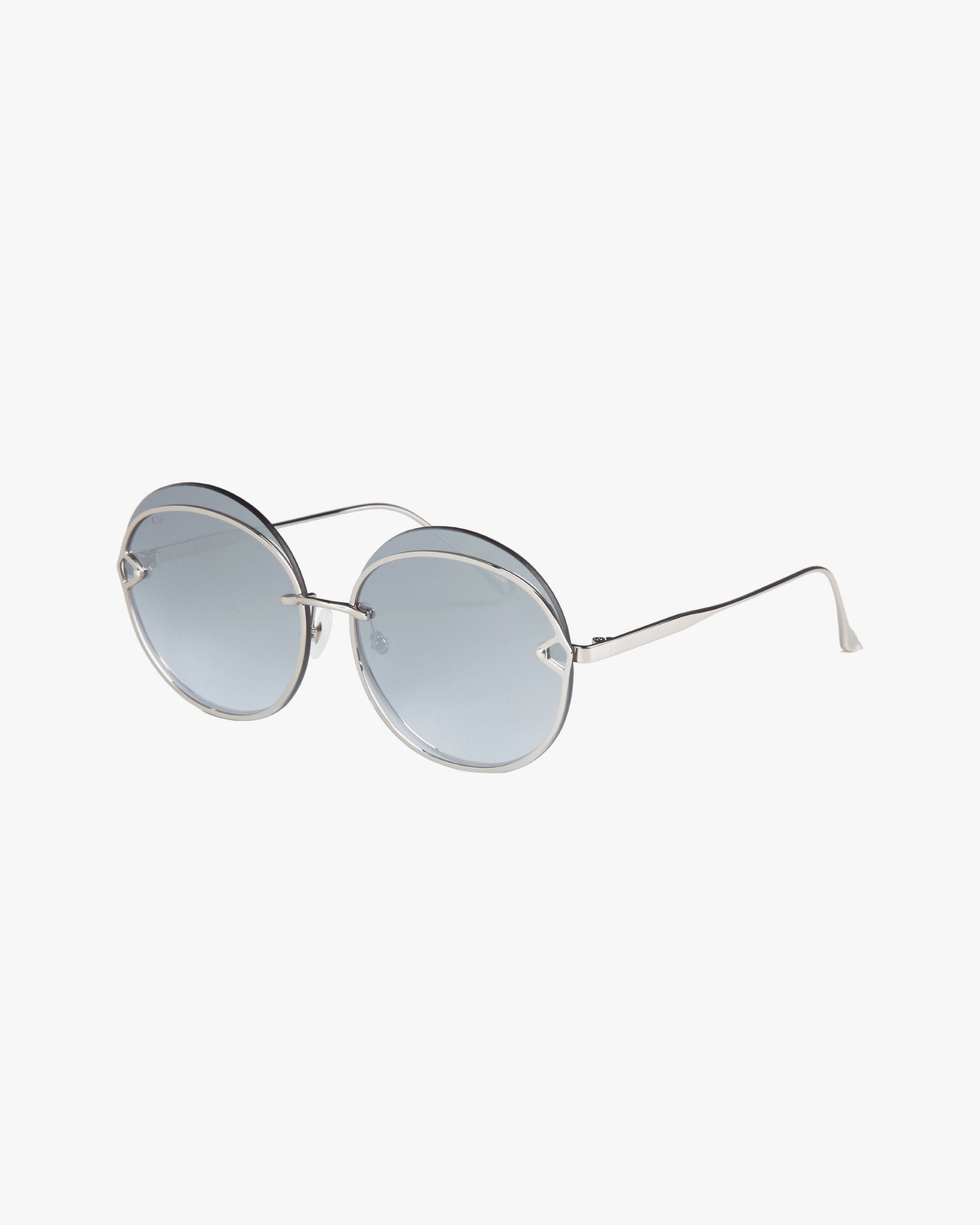 The Quartz sunglasses by For Art&#39;s Sake® feature round lenses made of light gray nylon, housed in thin stainless steel frames. These minimalist glasses have slightly curved temples with a glossy finish and UVB-protected lenses that offer a subtle tint for a shaded effect.