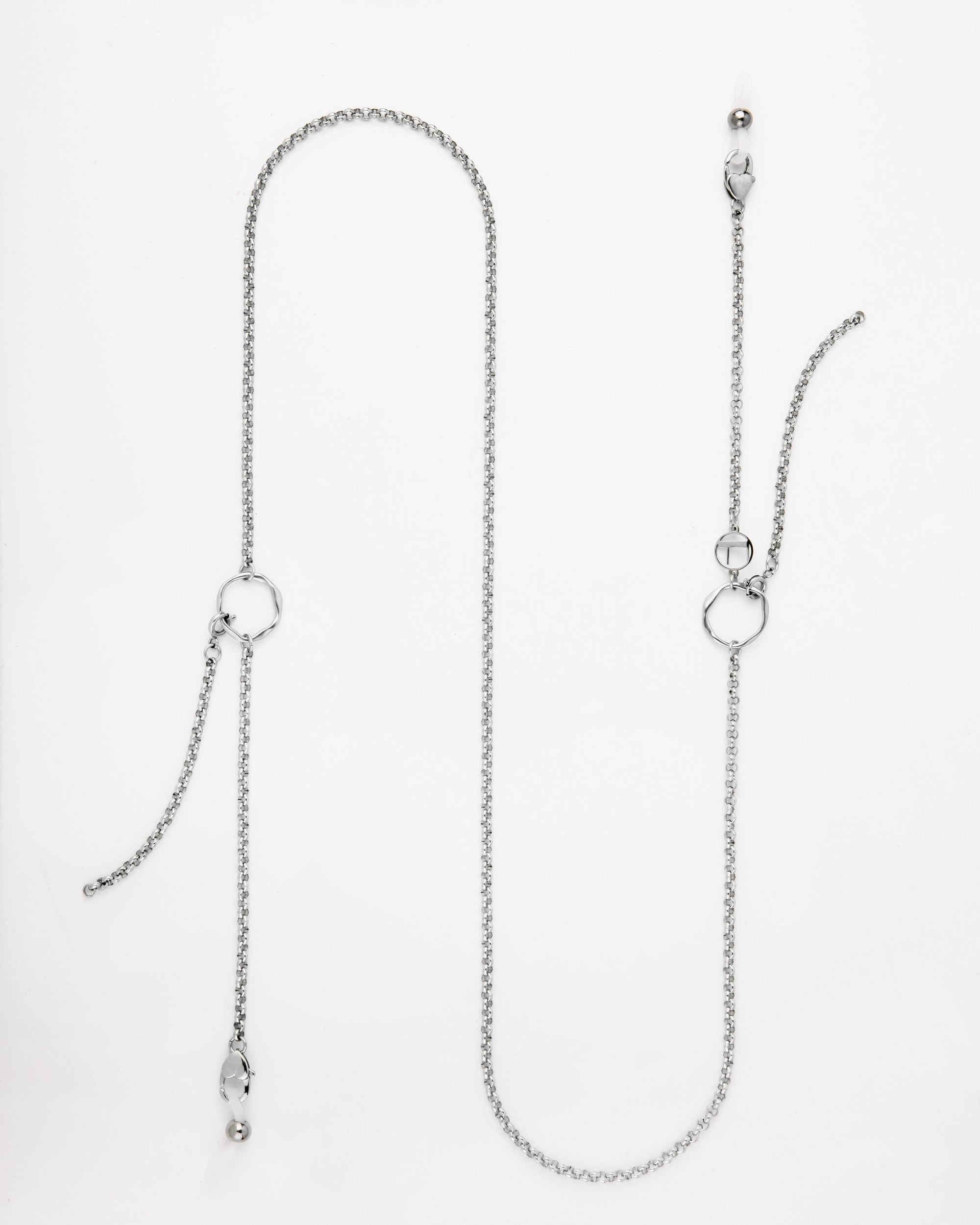 This image shows a long, delicate Florentina Glasses Chain by For Art&#39;s Sake®. The chain features two small geometric pendants and two dangling ends, each embellished with a small silver or pearl-like bead. The necklace is laid out flat against a plain white background.