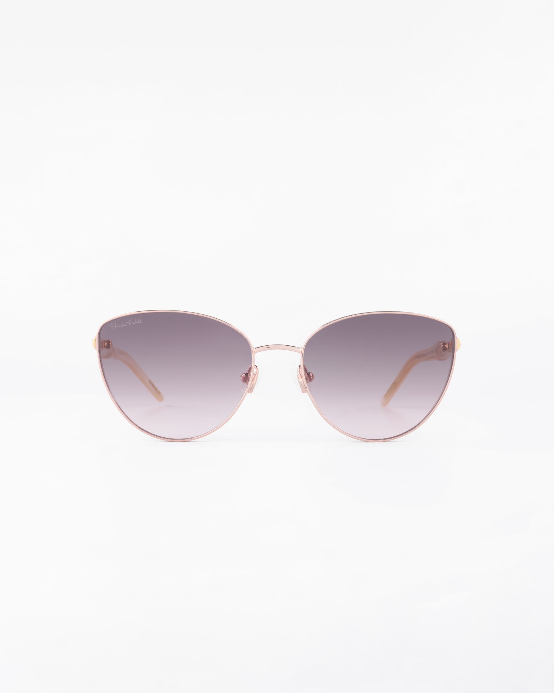 A pair of stylish Frida Brush sunglasses by For Art&#39;s Sake® with rose-gold frames and dark gradient, ultra-lightweight lenses. The arms, crafted from gold-plated stainless steel, are thin and elegant. Featuring UVA &amp; UVB protection, these Frida Brush sunglasses create a modern look against a white background.