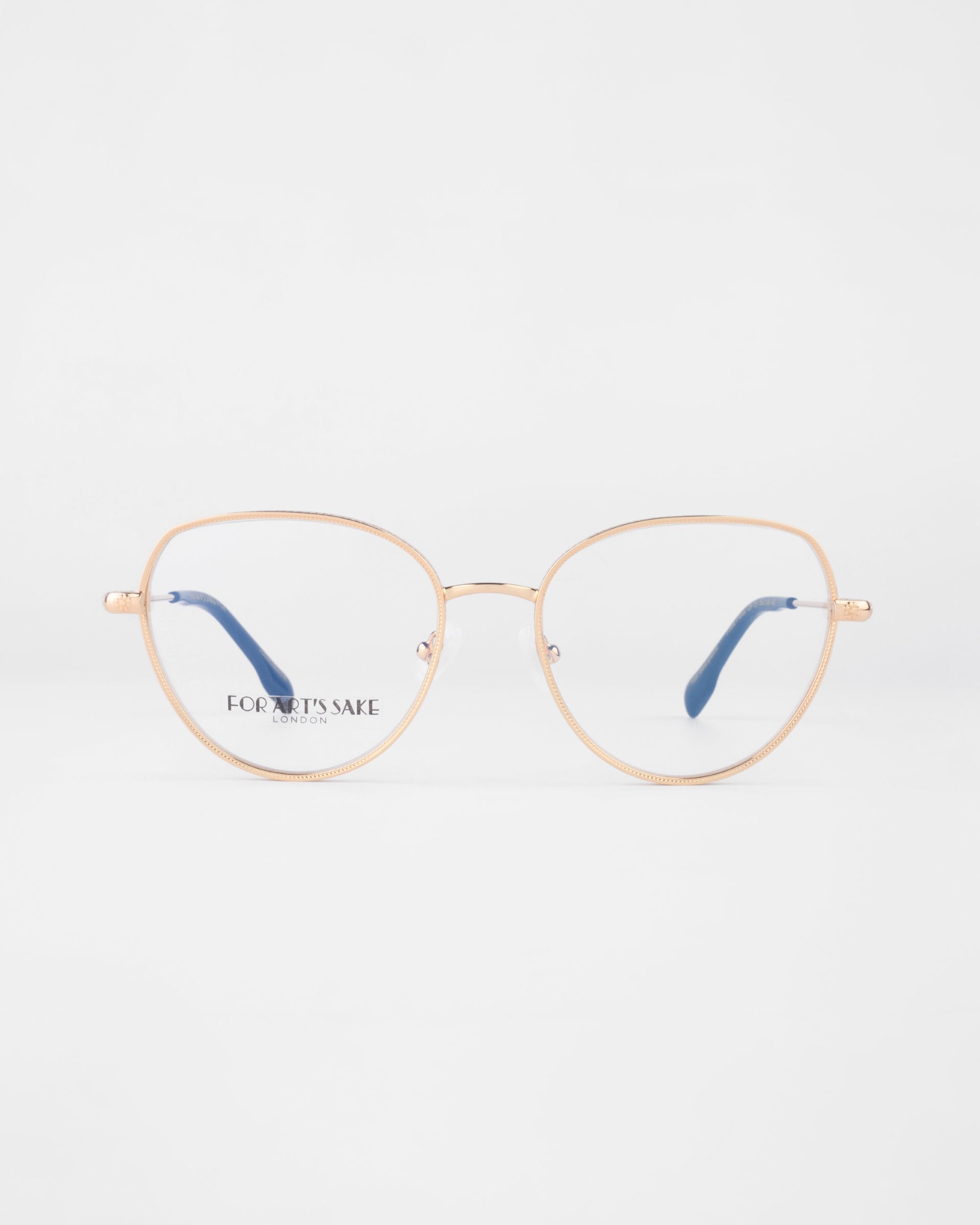 A pair of gold-framed eyeglasses with thin round prescription lenses and blue temple tips. The watermark text &quot;FOR ART&#39;S SAKE&quot; is visible on the left lens. The Frida Floral glasses from For Art&#39;s Sake®, fitted with a blue light filter, are set against a plain, light background.