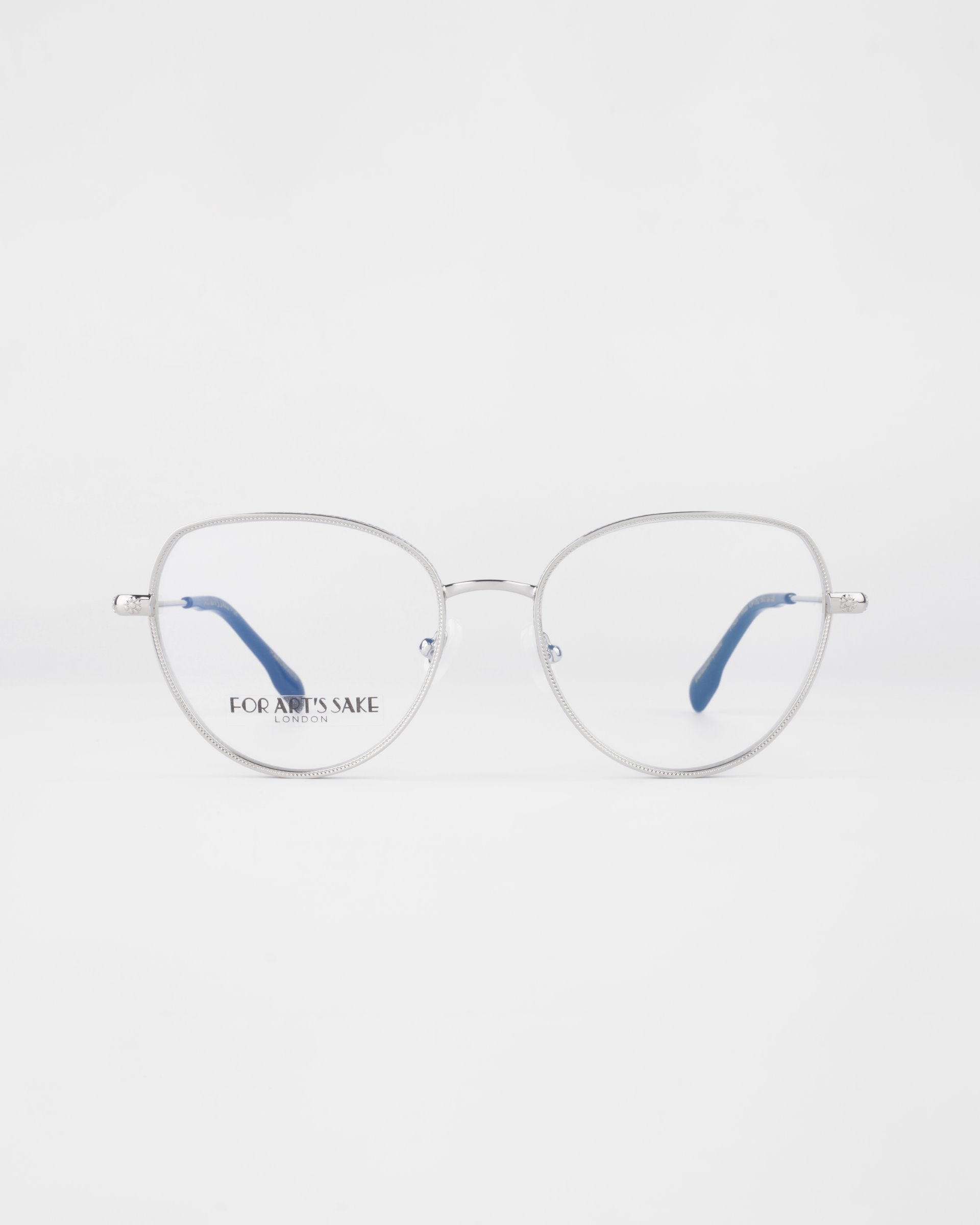 A pair of round, silver-framed Frida Floral eyeglasses with blue temple tips on a white background. The glasses feature thin metal frames and clear prescription lenses. The brand name &quot;For Art&#39;s Sake®&quot; is visible on the left lens.