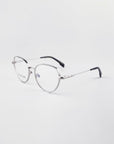 A pair of stylish round metal eyeglasses with a silver, 18-karat gold-plated frame and black temple tips, placed on a white background. The Frida Floral by For Art's Sake® glasses have thin, delicate frames and nose pads for comfort. Complete with blue light filter for extra eye protection.