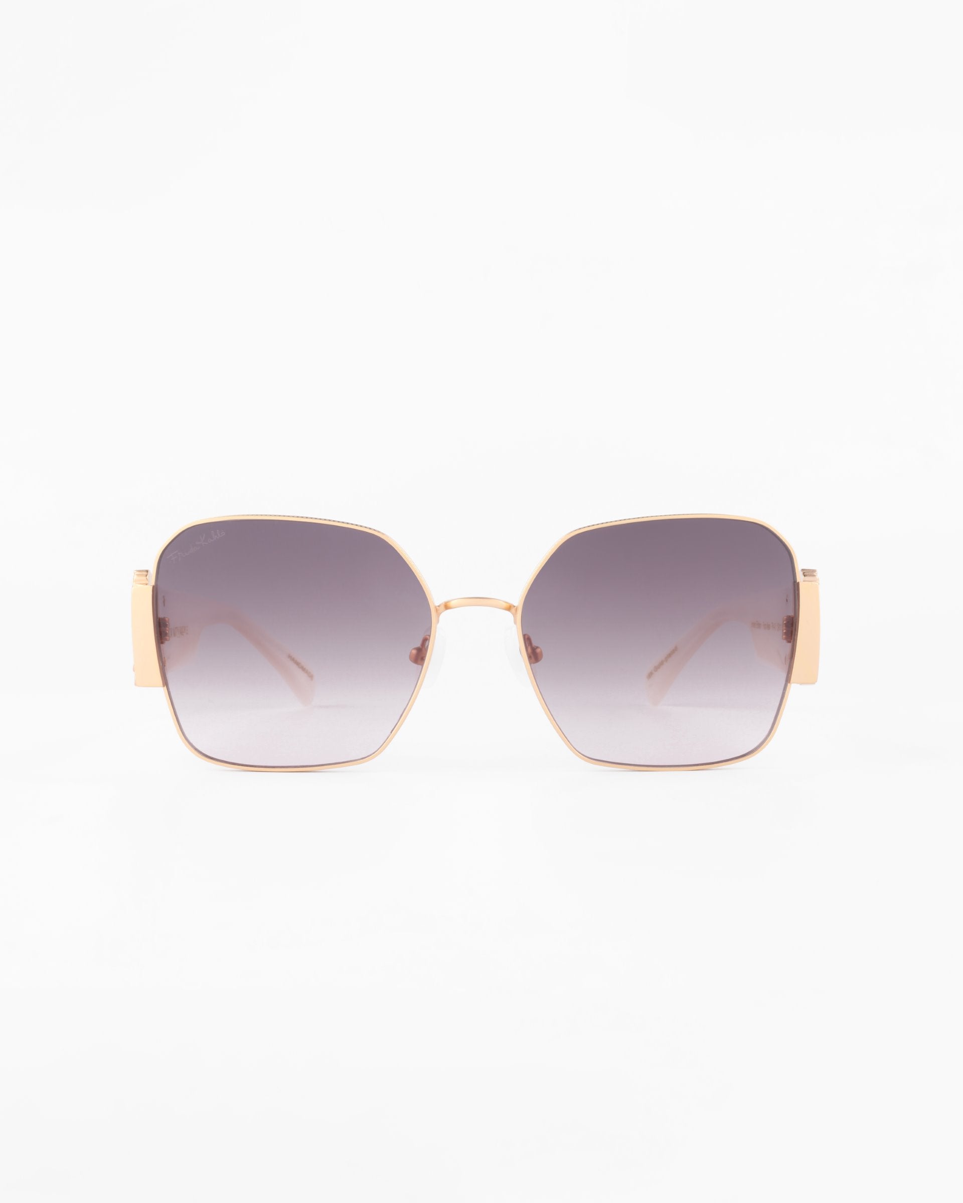 A pair of Frida Mask sunglasses by For Art's Sake® with large, square lenses that have a gradient tint from dark gray to clear. Made with gold-plated stainless steel and ultra-lightweight nylon lenses, they offer 100% UVA & UVB protection. The sunglasses have thin arms and a minimalist design, set against a white background.