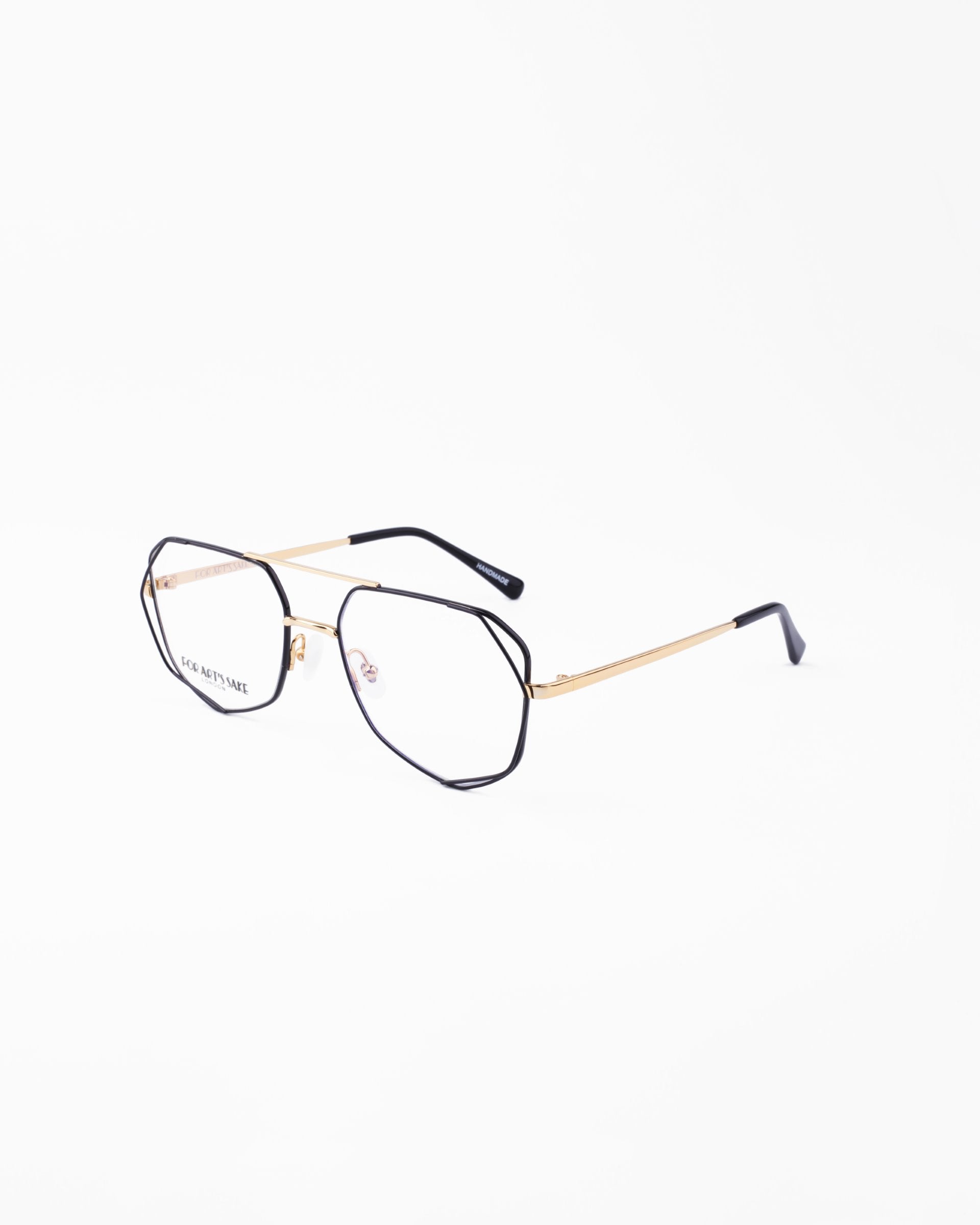 A pair of stylish Genius Two eyeglasses by For Art&#39;s Sake® with thin gold metal frames and black temple tips against a plain white background. The hexagonal lenses, equipped with a blue light filter, offer a modern and chic look while providing essential eye protection.