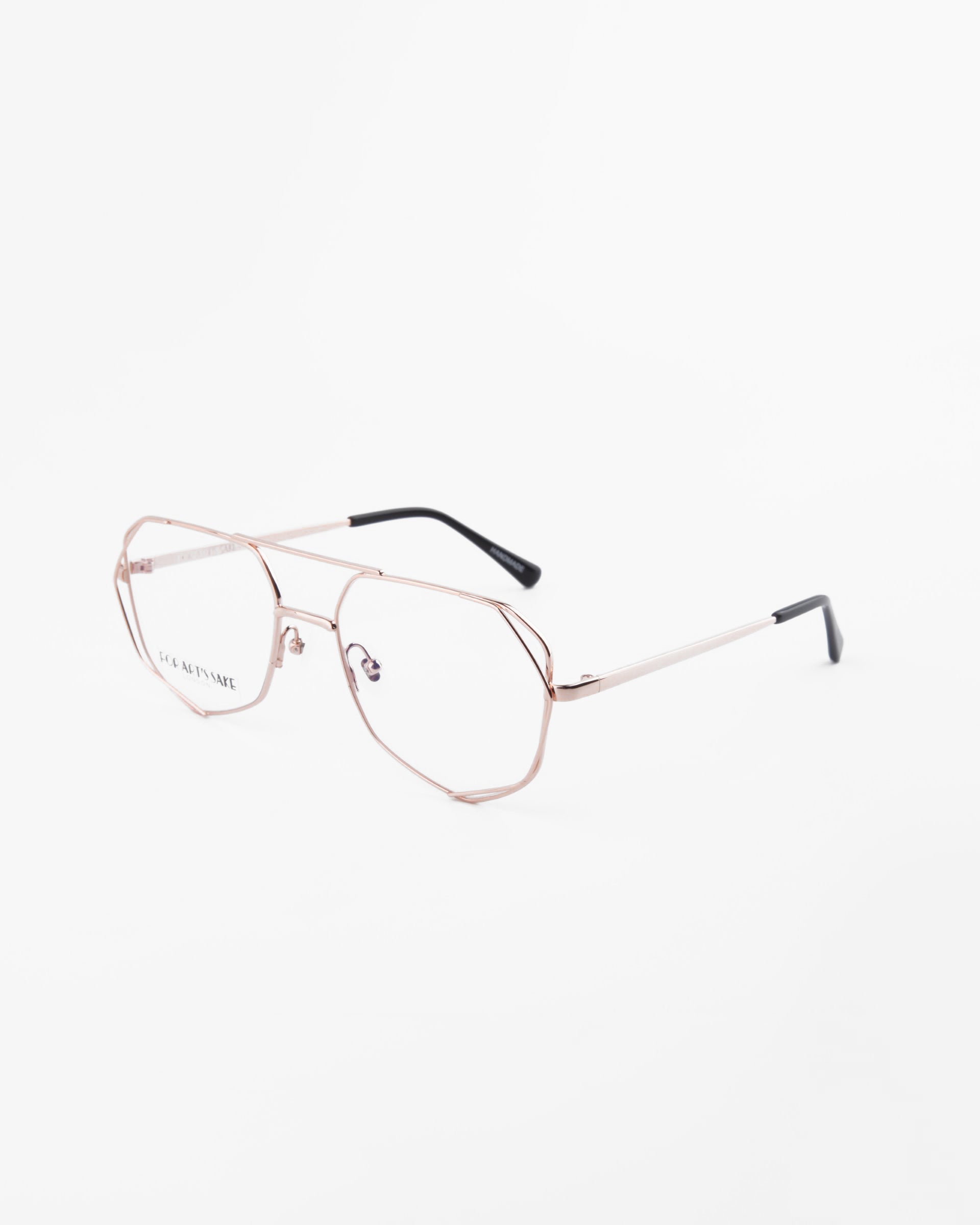 A pair of Genius Two metal-frame eyeglasses by For Art&#39;s Sake® with clear lenses featuring blue light filter technology. The frames are thin and gold-colored with black temple tips. The eyeglasses are photographed at a three-quarter angle on a white background.