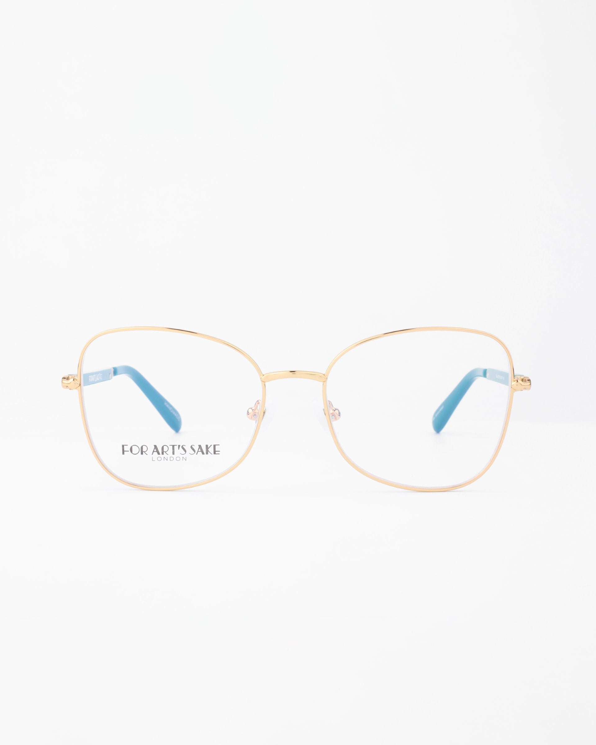 A pair of Grace eyeglasses by For Art&#39;s Sake® with thin, 18-karat gold-plated metal frames. The temples are gold with blue tips. The left lens has the phrase &quot;FOR ART&#39;S SAKE&quot; printed on it. The background is plain white, emphasizing the eyeglasses.