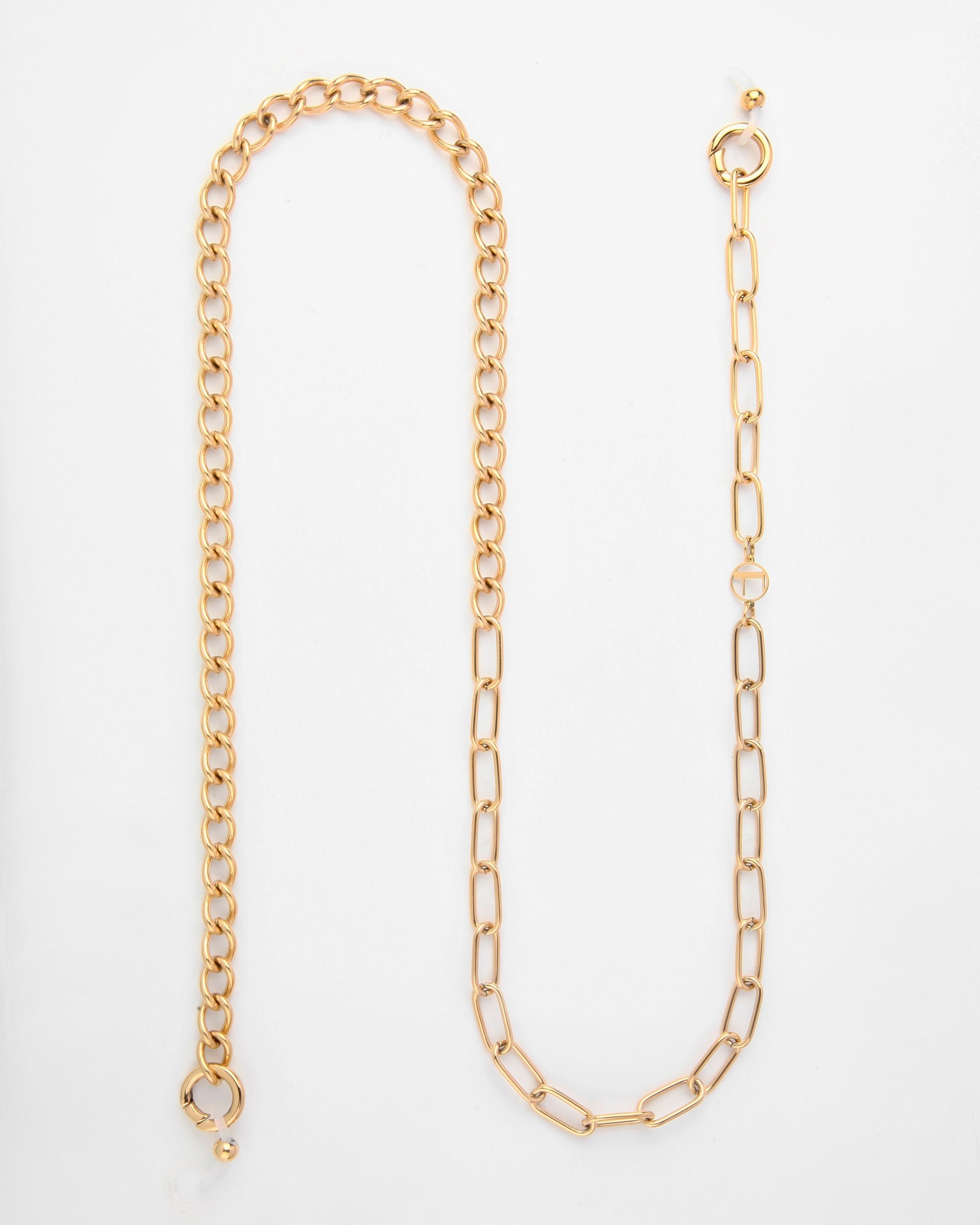 A For Art&#39;s Sake® Gabriel Glasses Chain crafted with 18K gold-plated links lies on a white surface. One side features tightly packed circular links, while the other side has larger, elongated rectangular links. Both ends have circular clasps, and one end is adorned with a small orb.