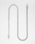 A silver Gabriel Glasses Chain by For Art's Sake® is laid out on a white background. The chain has a mix of different link styles, with one half featuring elongated links and the other half comprising denser, rounded links. There are two clasping mechanisms on either end.