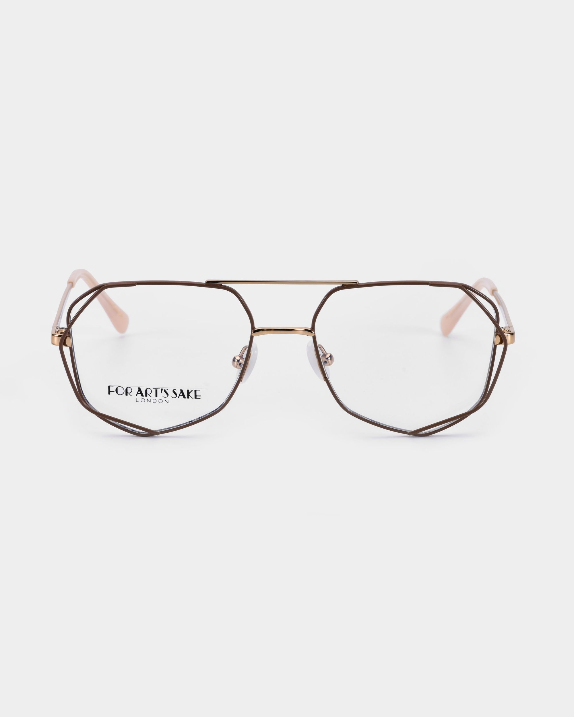 A pair of Genius Two geometric eyeglasses with a thin metallic frame. The lenses, equipped with a blue light filter, are clear, and the arms have a light finish. The brand name &quot;For Art&#39;s Sake®&quot; is visible on one of the lenses, and the background is plain white.