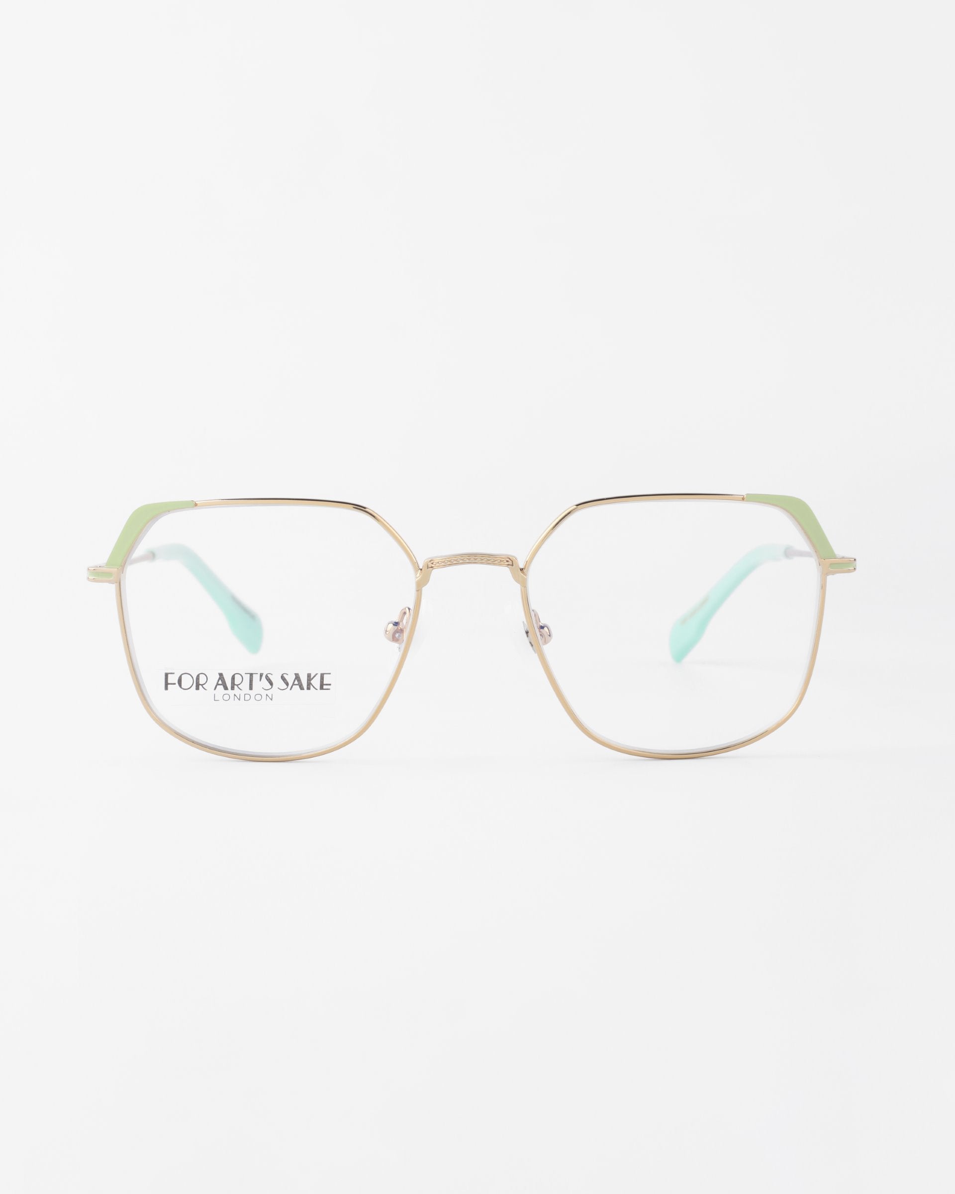 A pair of eyeglasses with a thin metallic frame featuring a hexagonal shape. The temples are light green, and there is text on the left lens reading &quot;FOR ART&#39;S SAKE LONDON&quot;. These stylish Godiva glasses from For Art&#39;s Sake® offer UVA &amp; UVB protection, perfect for sunny days. The background is plain white.