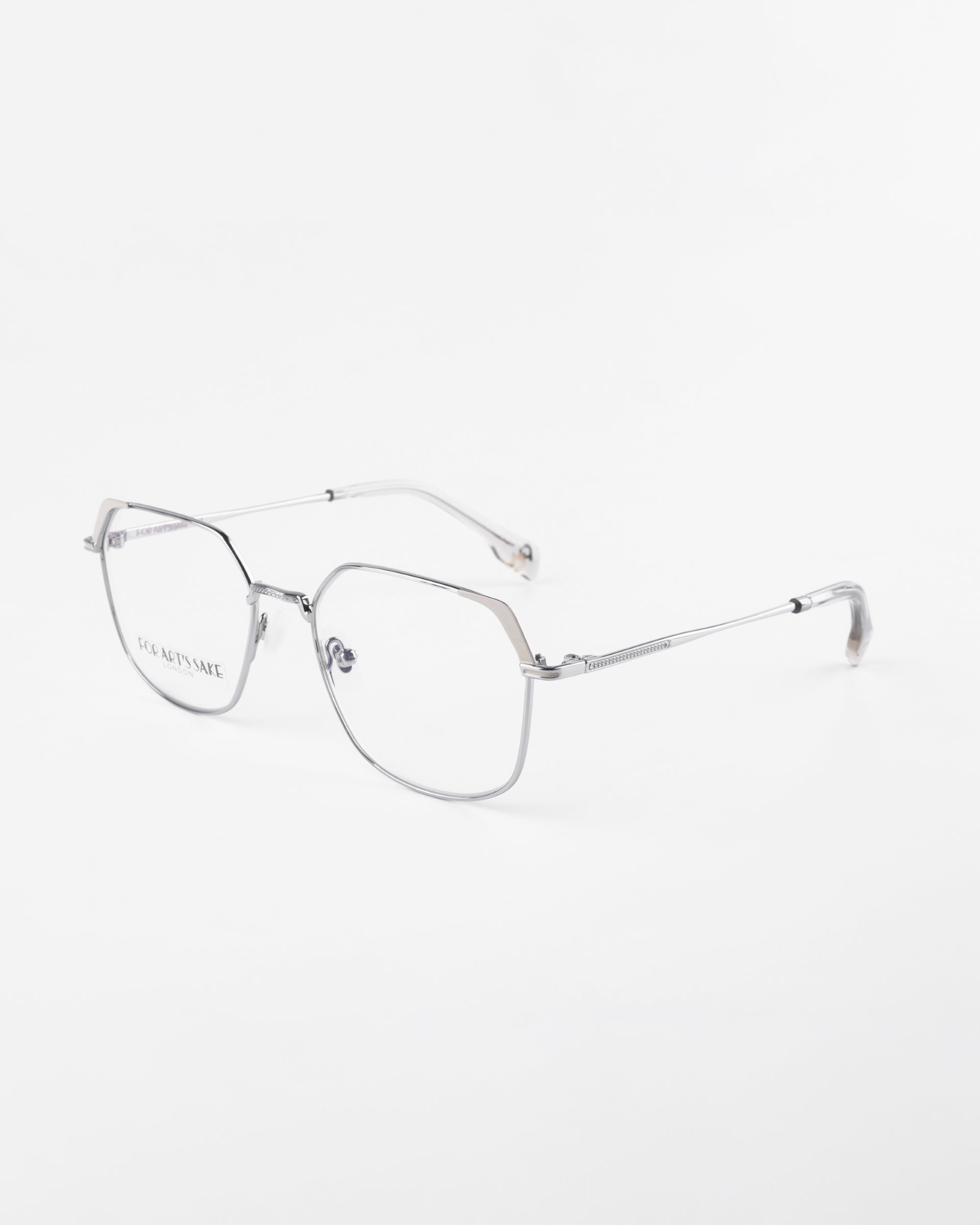 A pair of silver metal eyeglasses with a minimalist design on a white background. The frames have a thin, rounded rectangle shape with clear prescription lenses featuring a blue light filter, adjustable nose pads, and slim arms. The brand name &quot;For Art&#39;s Sake®&quot; is visible on the left lens.