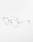 A pair of silver metal eyeglasses with a minimalist design on a white background. The frames have a thin, rounded rectangle shape with clear prescription lenses featuring a blue light filter, adjustable nose pads, and slim arms. The brand name "For Art's Sake®" is visible on the left lens.