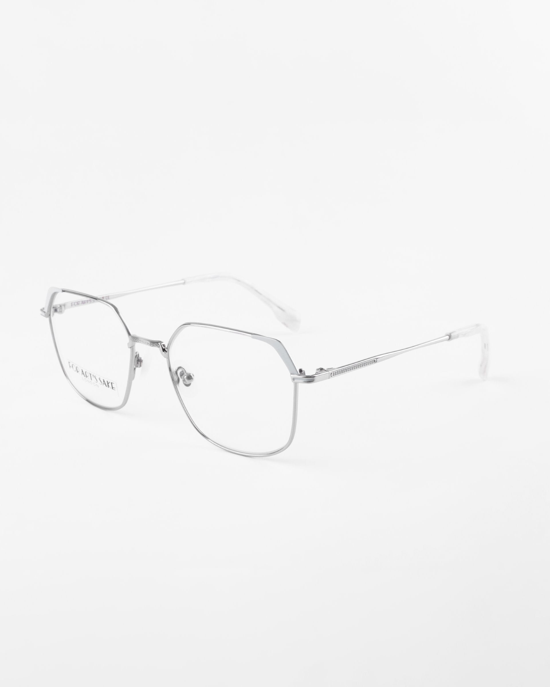 **For Art&#39;s Sake® Godiva:**

A pair of sleek, silver metal glasses with a minimalist design. The frames are thin and angular, featuring a slight geometric shape. Equipped with prescription lenses, the arms are straight with a subtle hinge near the lenses, and the nose pads are clear. The background is plain white.


