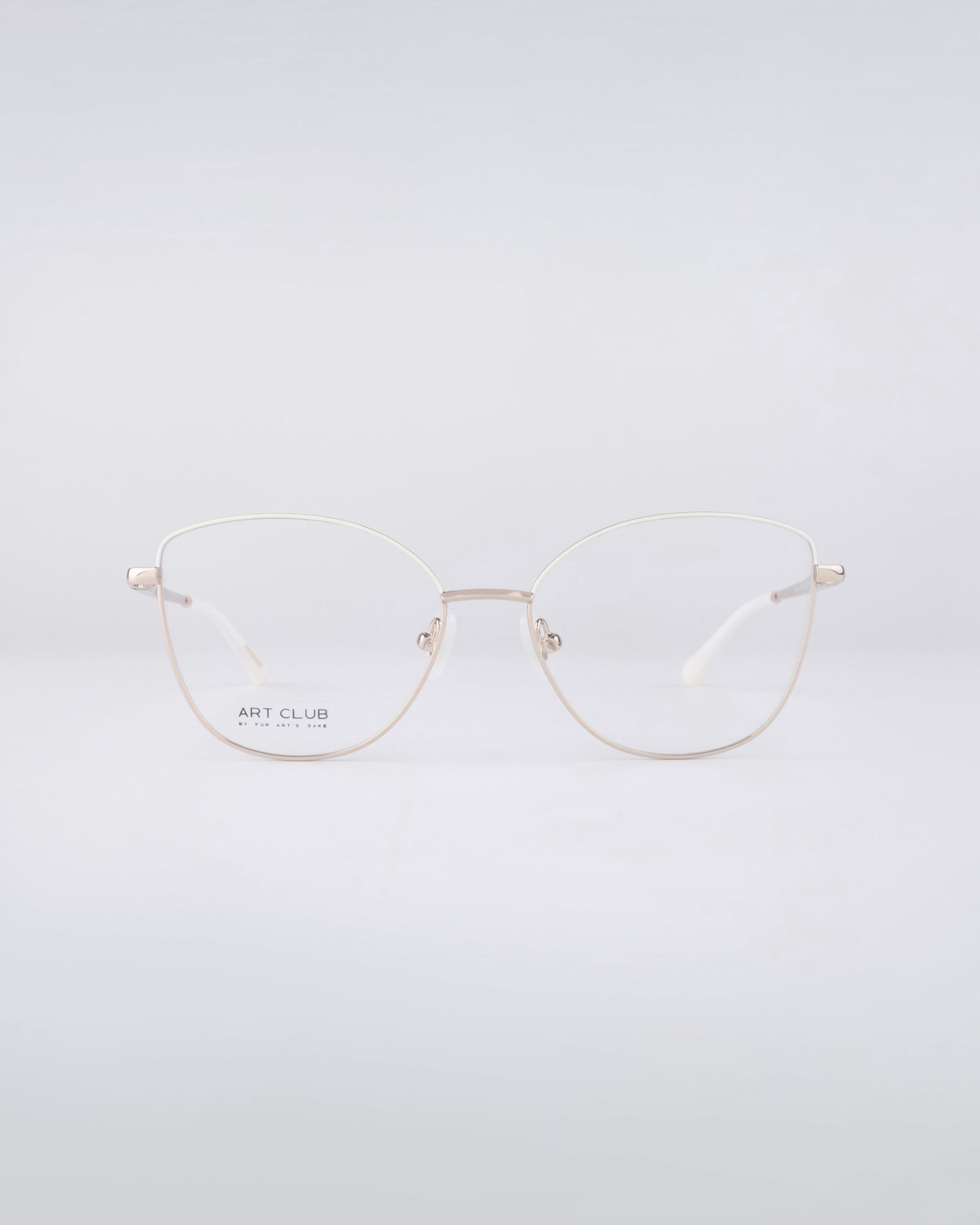 A pair of thin-rimmed eyeglasses with gold wireframes and blue light filter lenses, beautifully known as Greta frames from For Art&#39;s Sake®, are displayed against a light gray background.