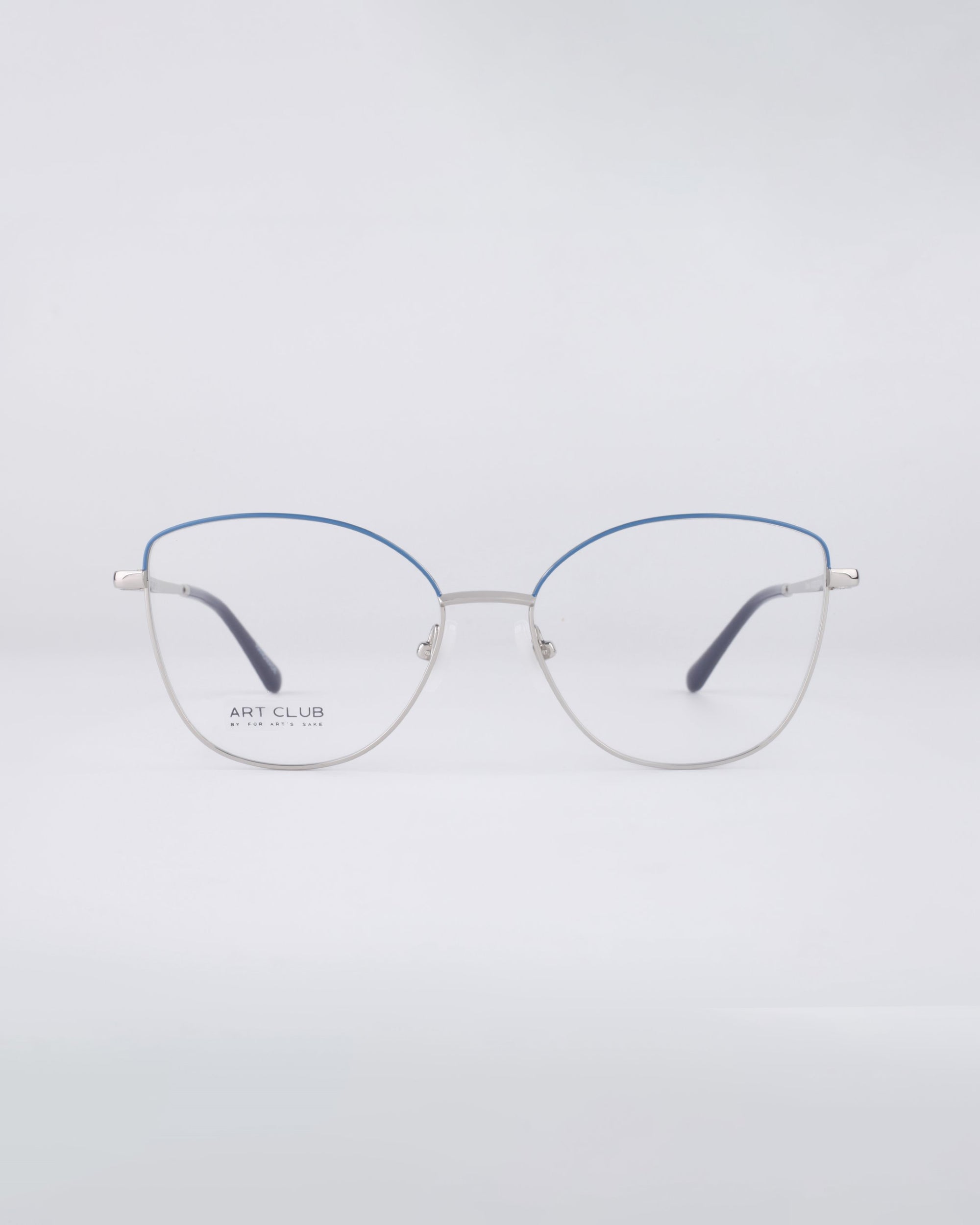 Introducing the Greta eyeglasses by For Art&#39;s Sake®: These stylish frames boast thin, metallic silver construction with chic blue accents on the top rim. Designed with a modern, minimalist aesthetic, they offer sustainable luxury and come equipped with blue light filter lenses, all set against a light gray backdrop.