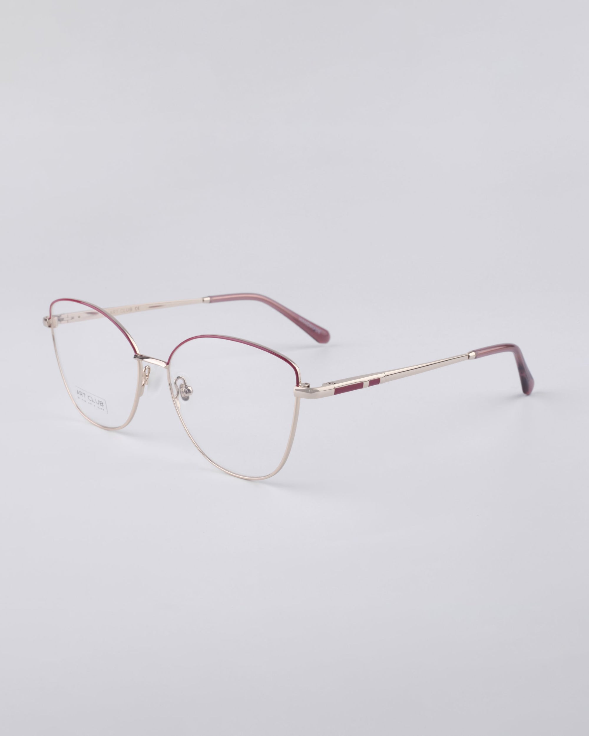 A pair of chic Greta frames by For Art&#39;s Sake® showcases a slim gold metal frame accented with maroon on the temple arms. The lenses are equipped with a blue light filter, presenting sustainable luxury against a simple white backdrop.