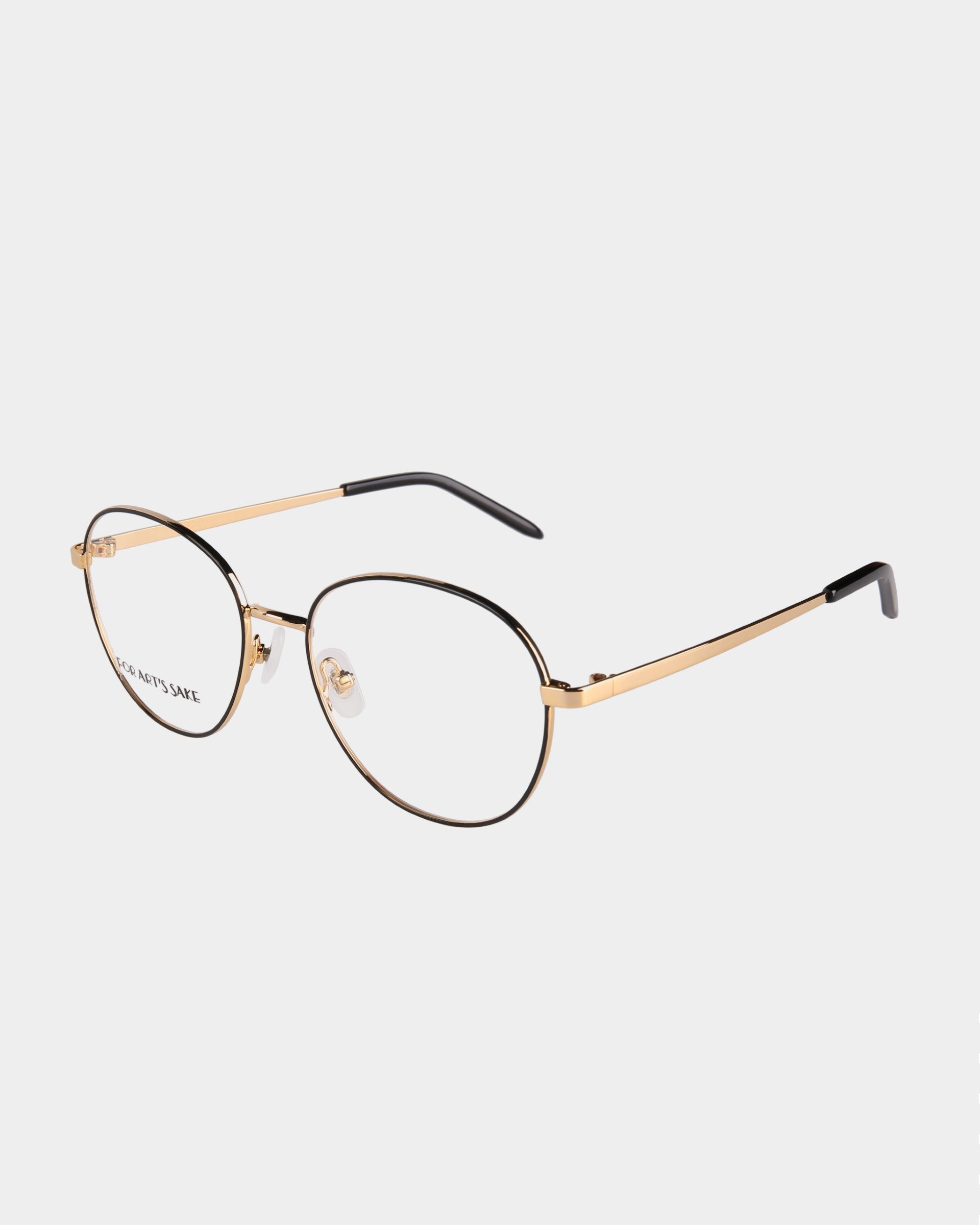 A pair of stylish eyeglasses with thin gold-toned metal frames, black detailing on the top rim, and black temple tips. The lenses are round with a slightly geometric shape and feature adjustable nose pads. "Hailey" by For Art's Sake® is partially visible on the left lens. The background is white.